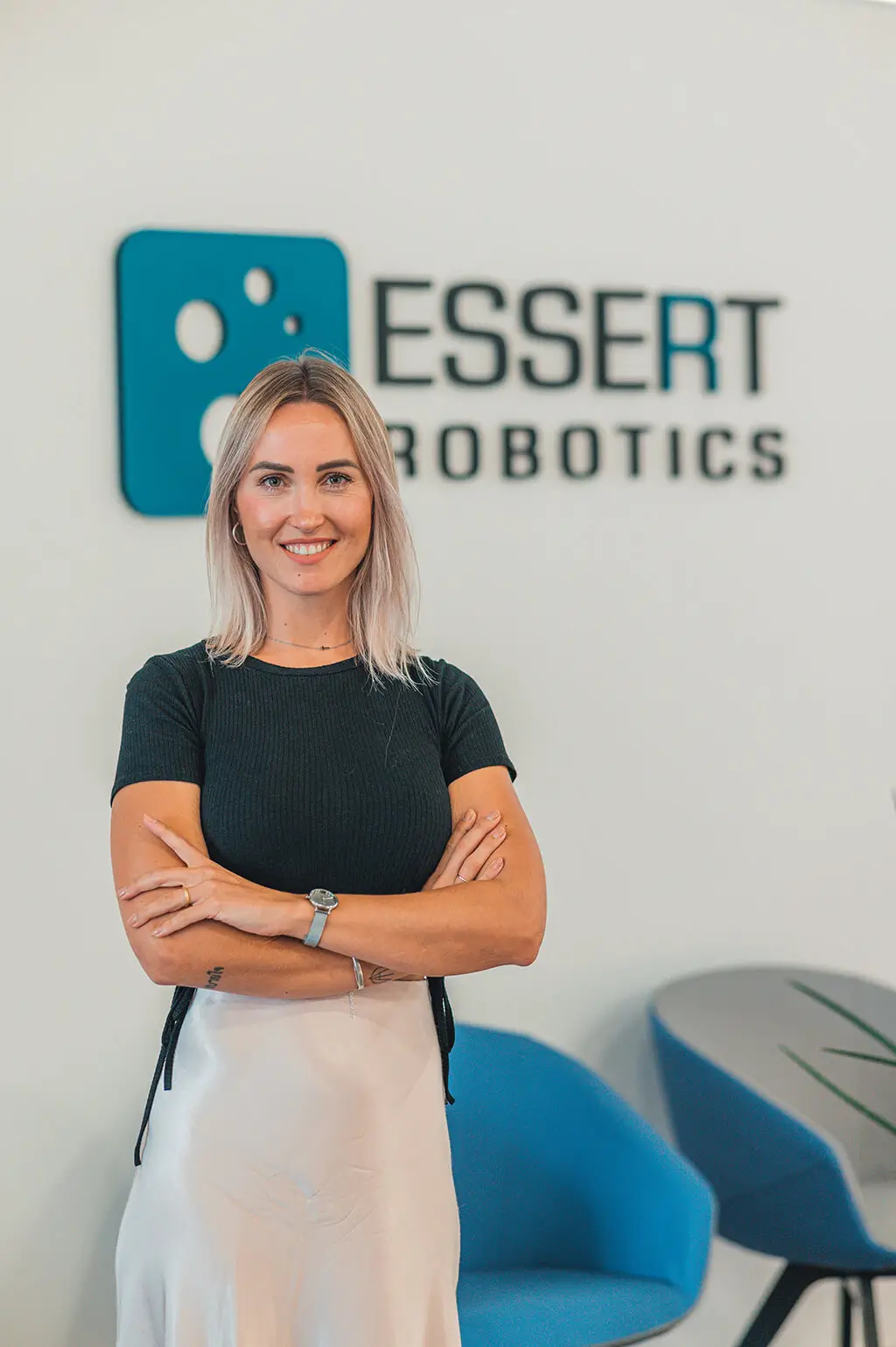Woman smiling at the camera in front of the ESSERT Robotics logo