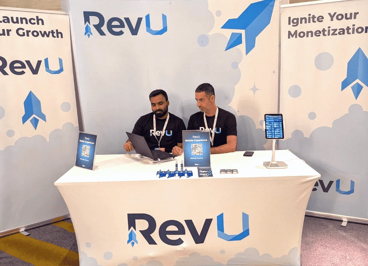 RevU staff demonstrating their offerwall at a trade show booth.
