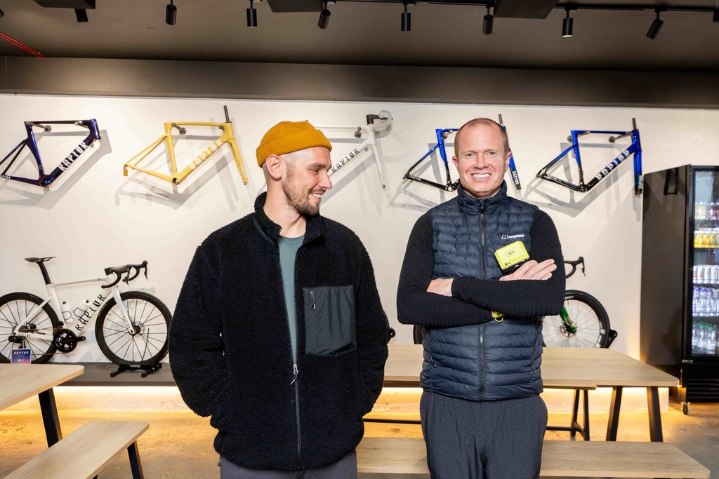 two business owners smile in a bike shop, one of them holds a Teya card machine