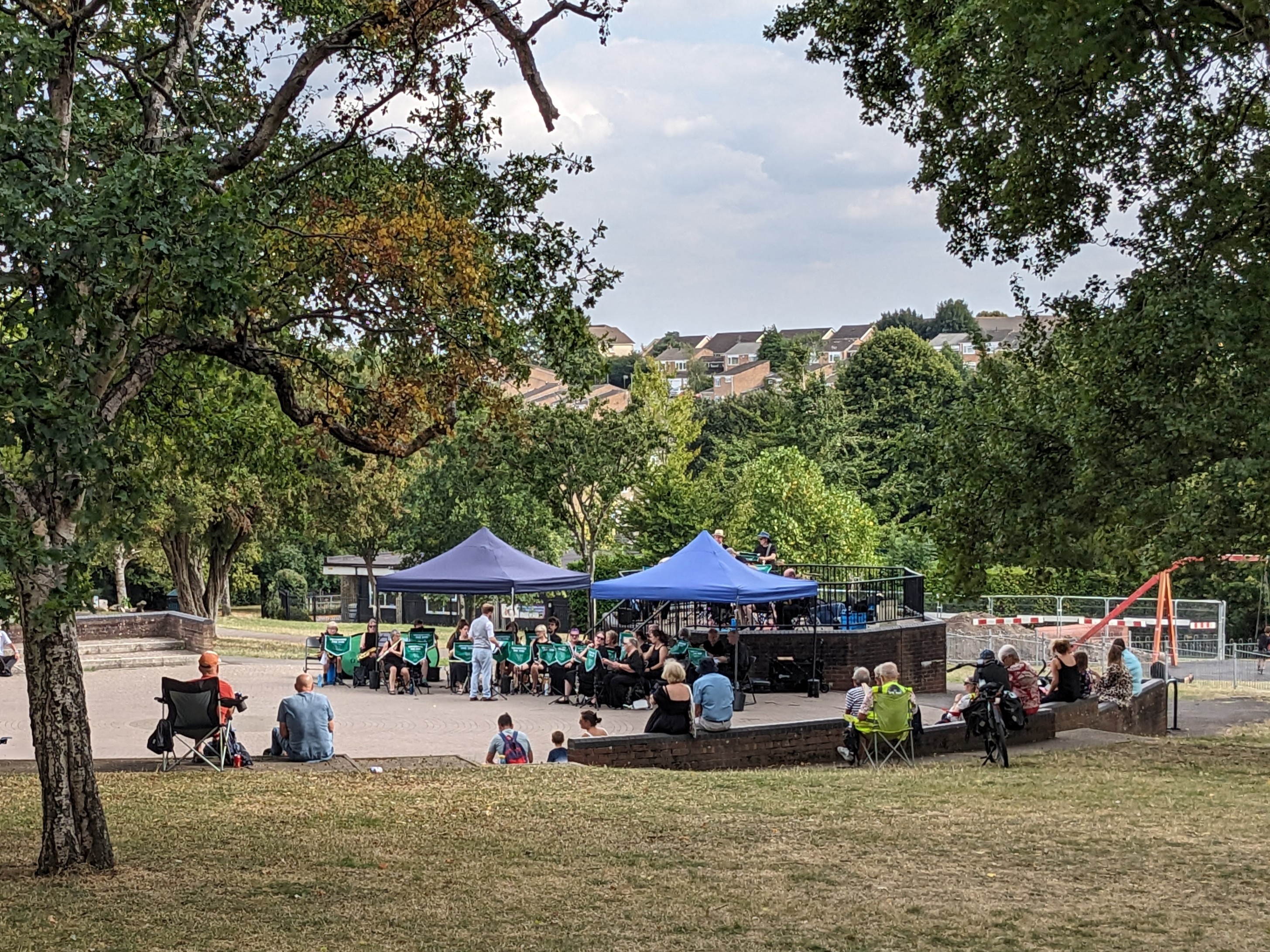 Musicians playing under two gazebos in a park