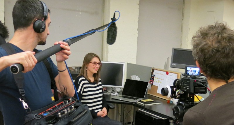 A photo of a group of people filming a scene in an office.