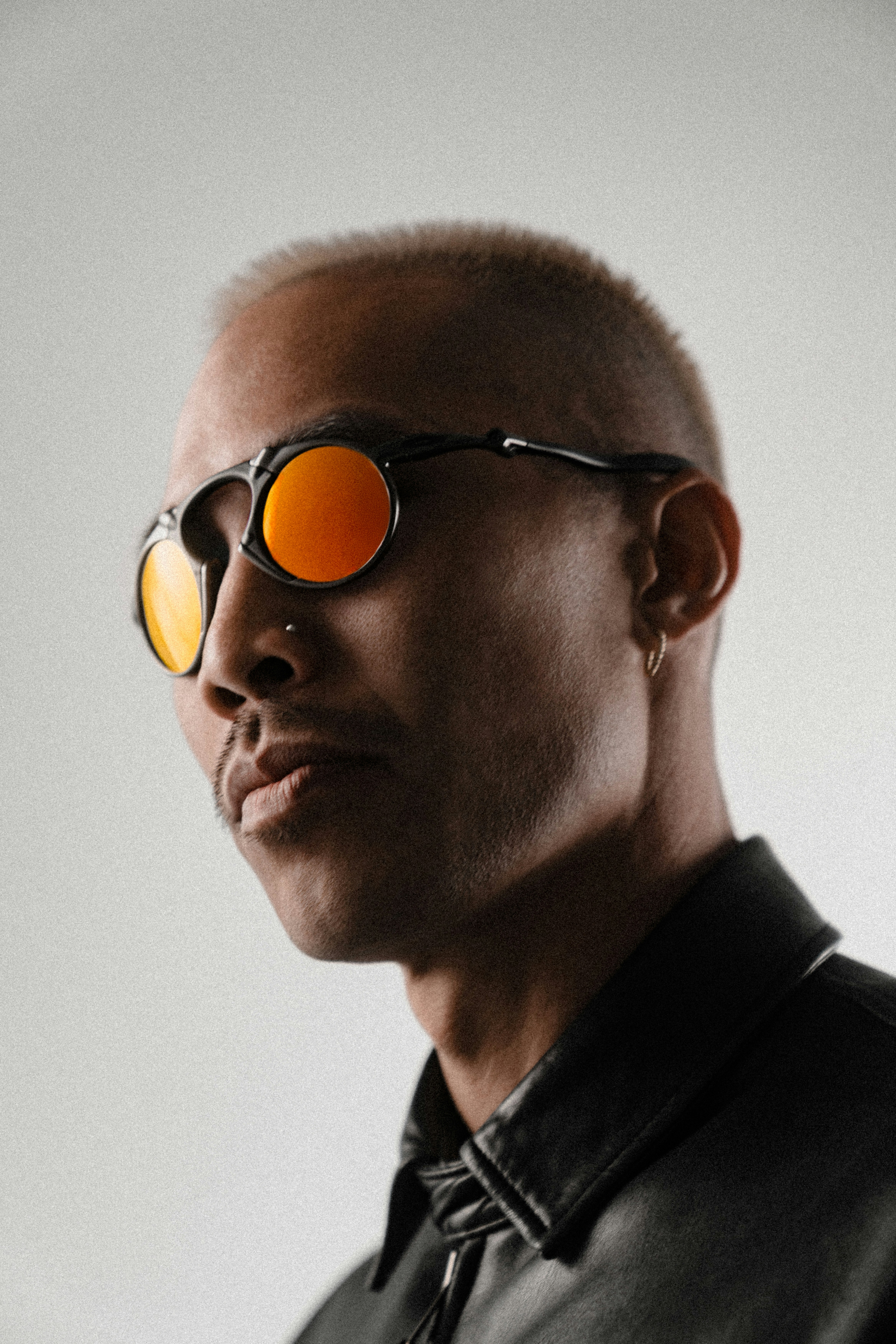 Man wearing round orange sunglasses and black jacket