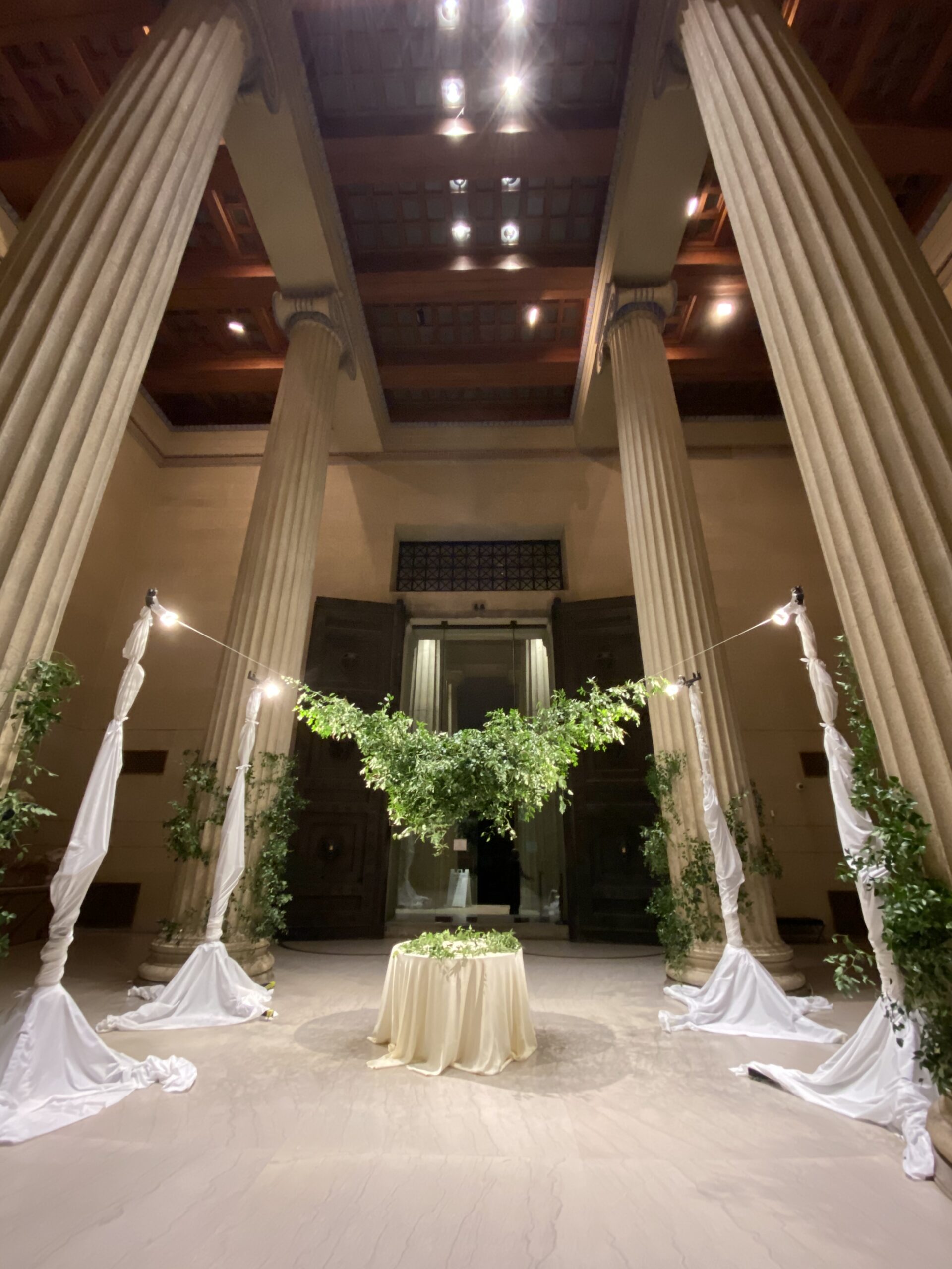 Elegant columned atrium venue with a draped accent table and greenery