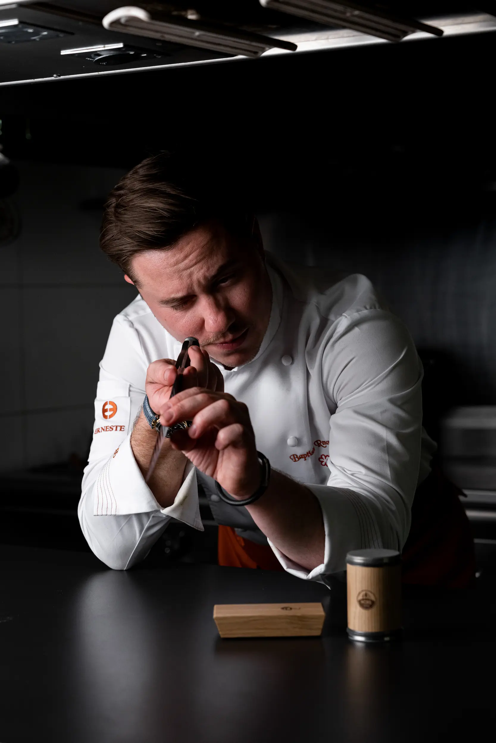 A chef carefully inspecting the sharpness of a knife edge after the sharpening process.