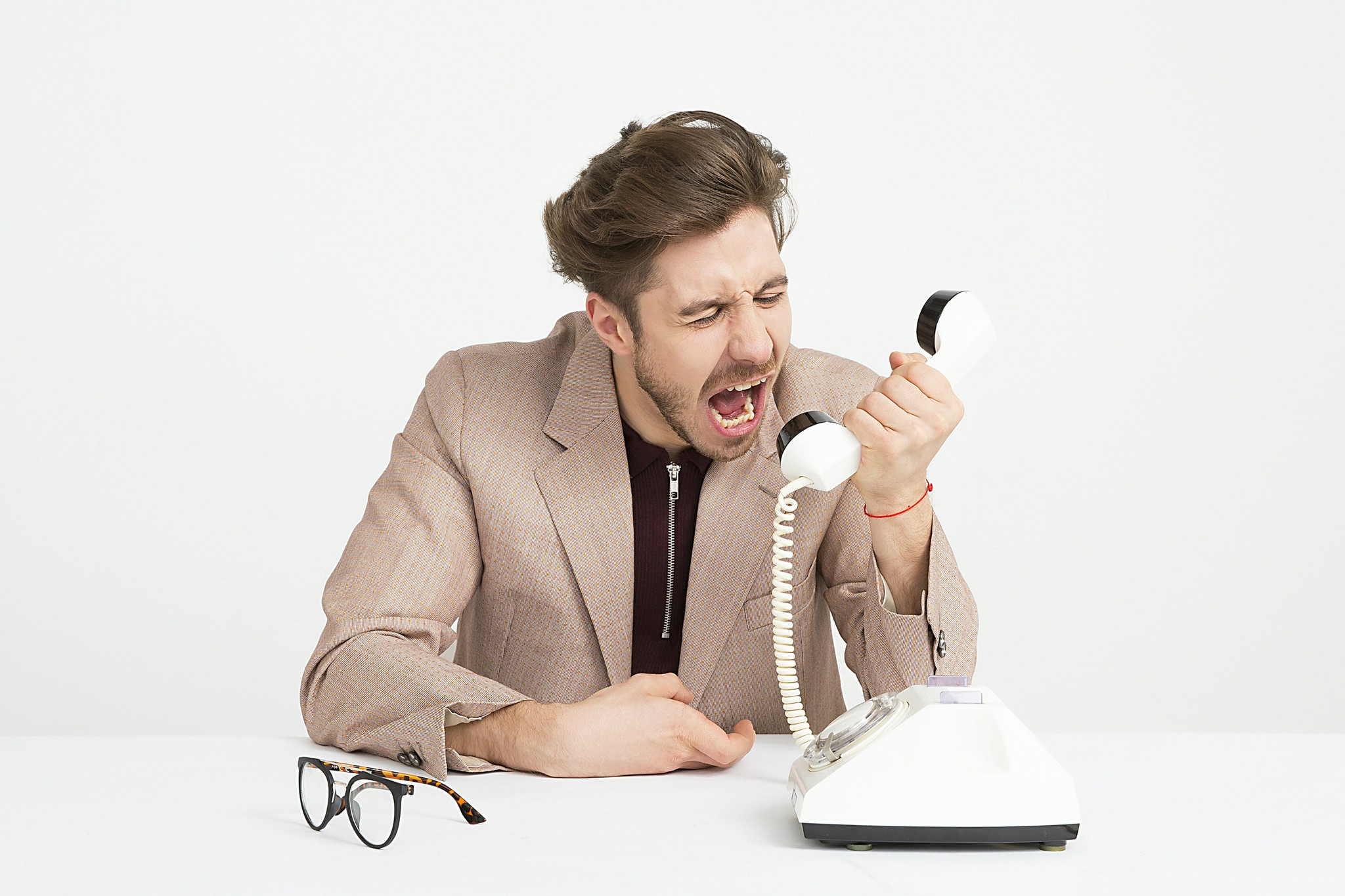 Photo of a man yelling at a rotary telephone