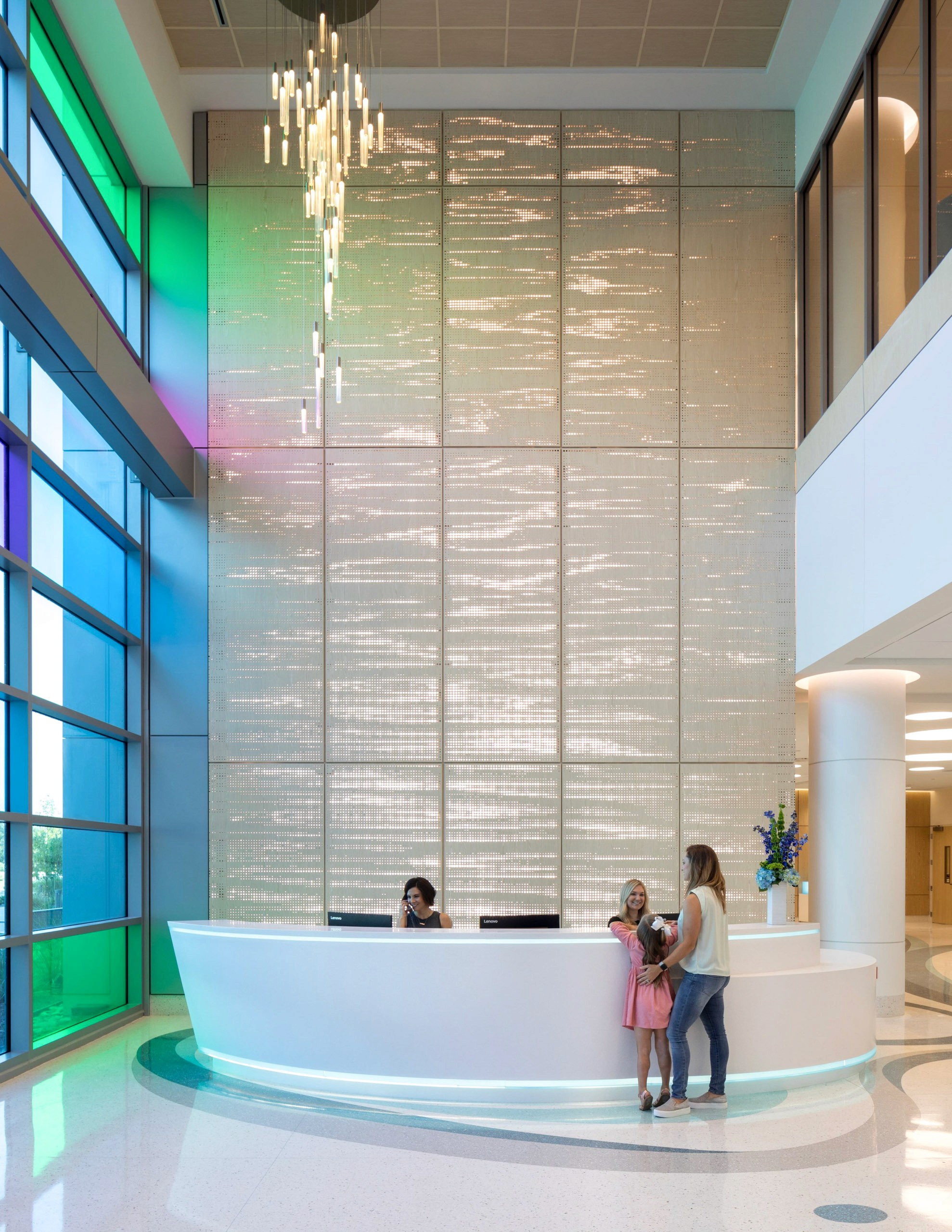 Modern reception desk with colorful windows and light fixture.