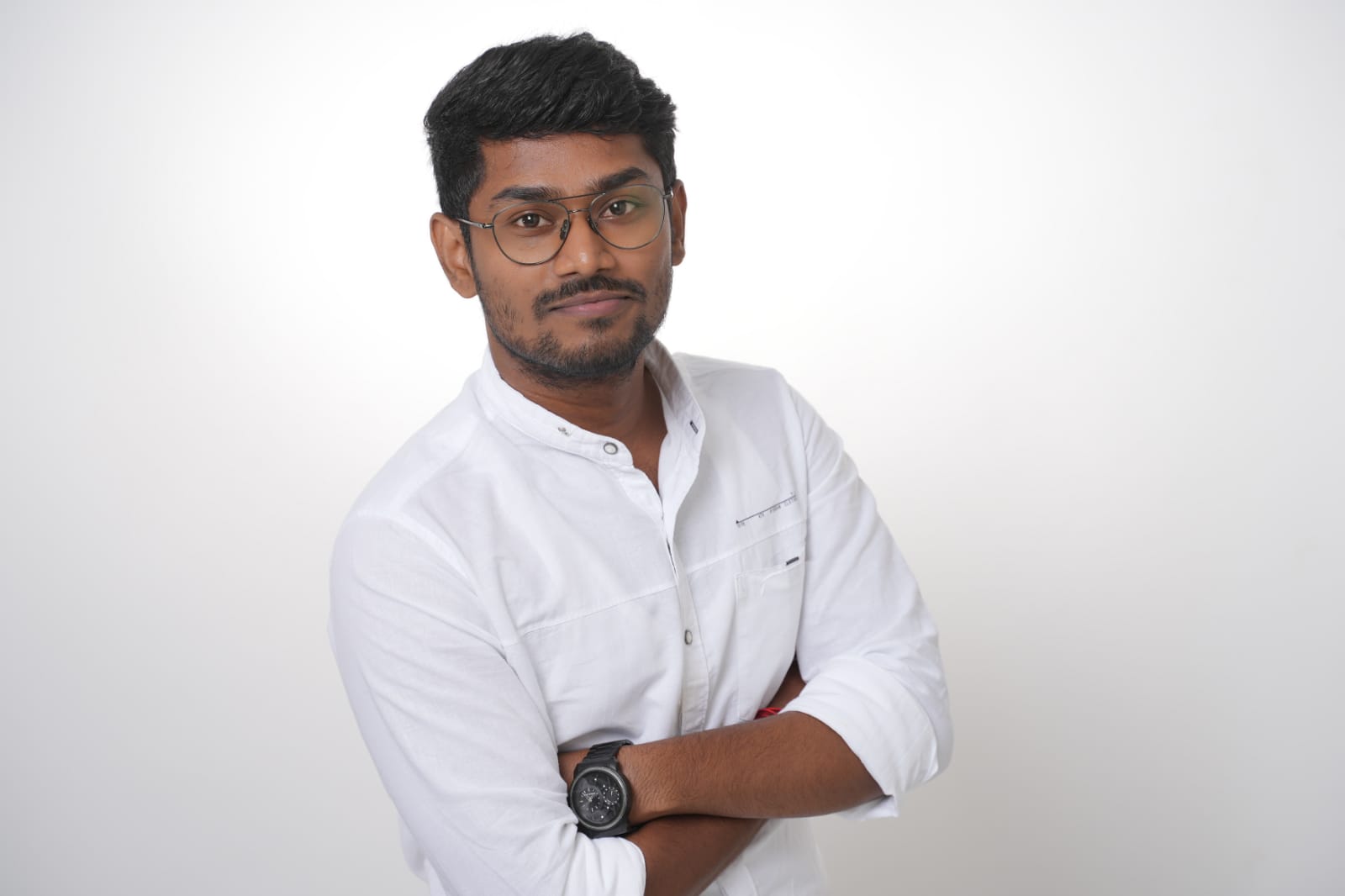 A young woman with long hair smiles while standing against a green backdrop, wearing a casual dark sweater.
