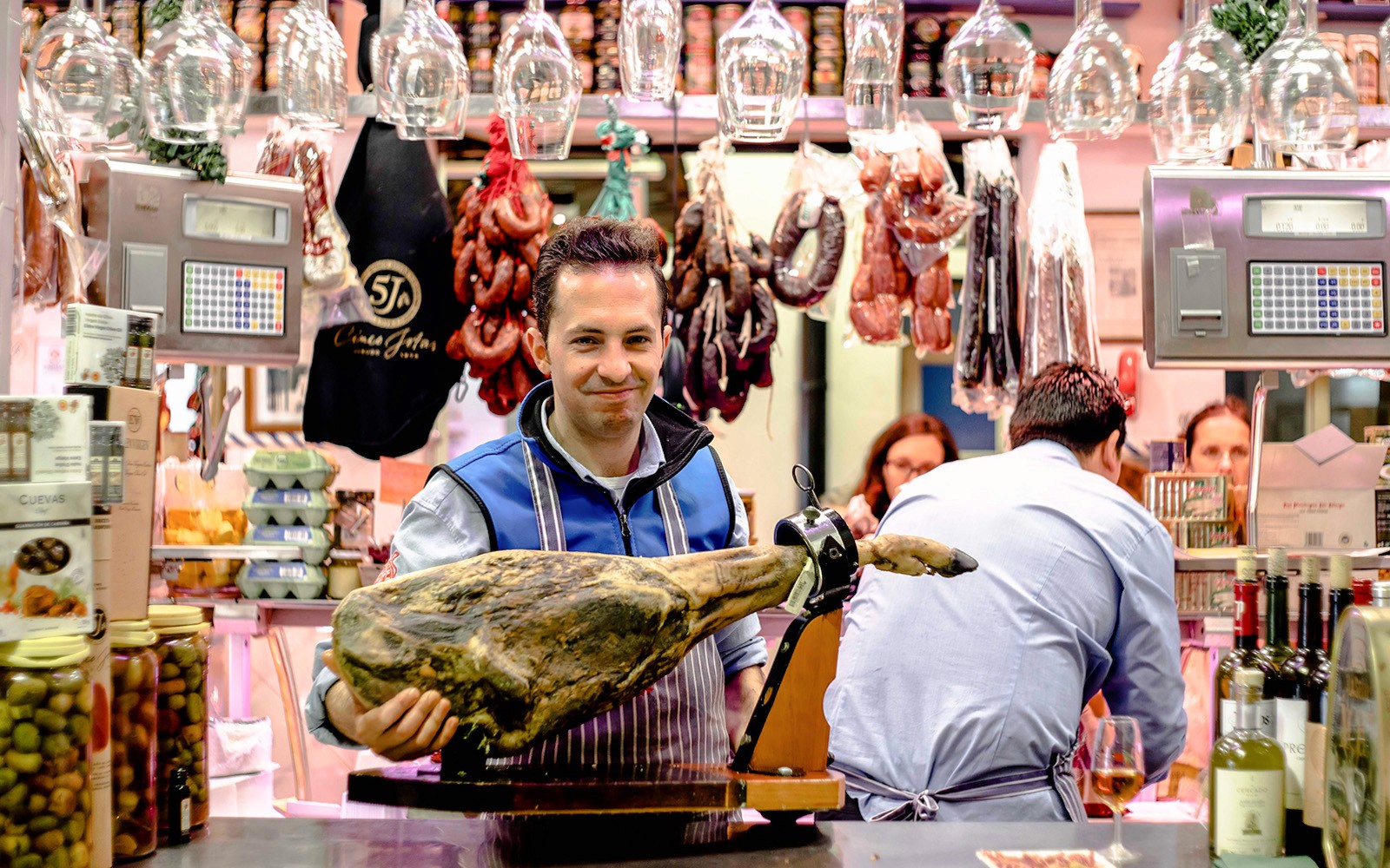 Man presenting cured ham at a tapas bar in Seville during a tasting tour.