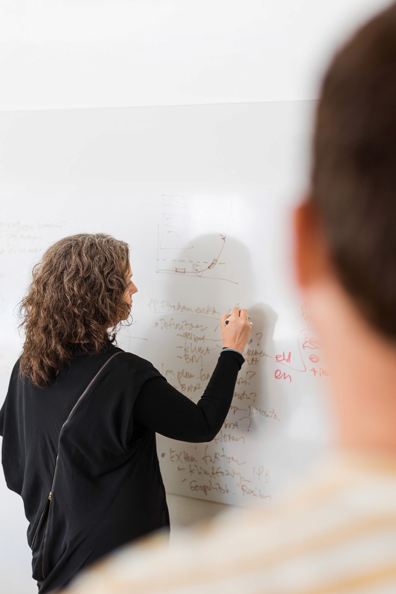 A smiling young man with crossed arms, wearing a plaid shirt and white t-shirt, poses against a dark background.