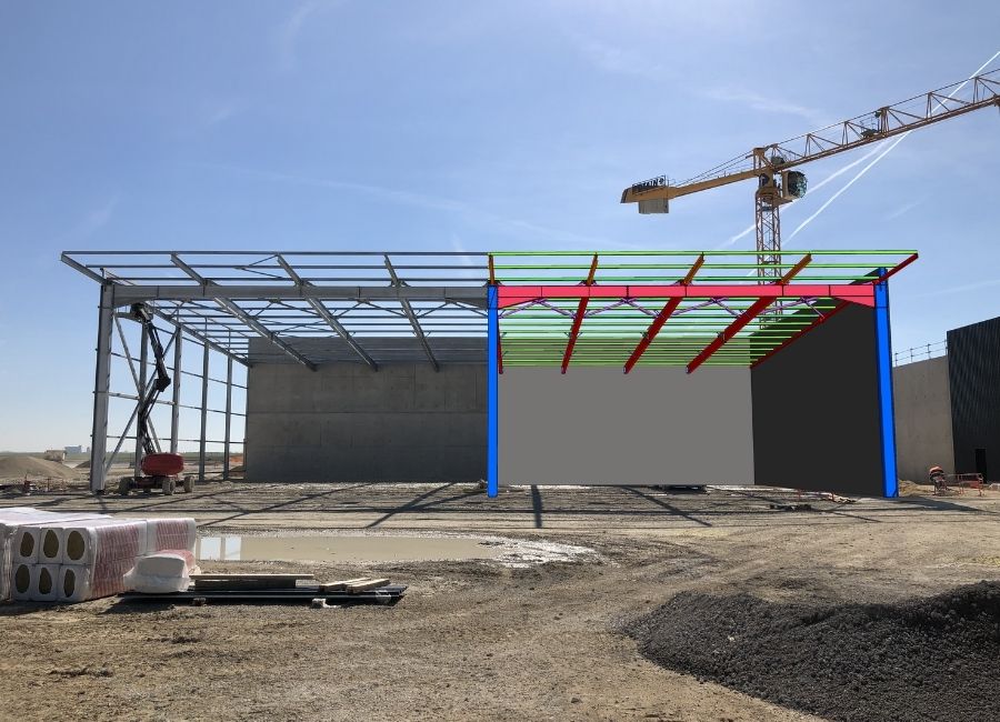 Grue positionnant un élément de bardage coloré en 3D sur une façade de bâtiment en chantier.