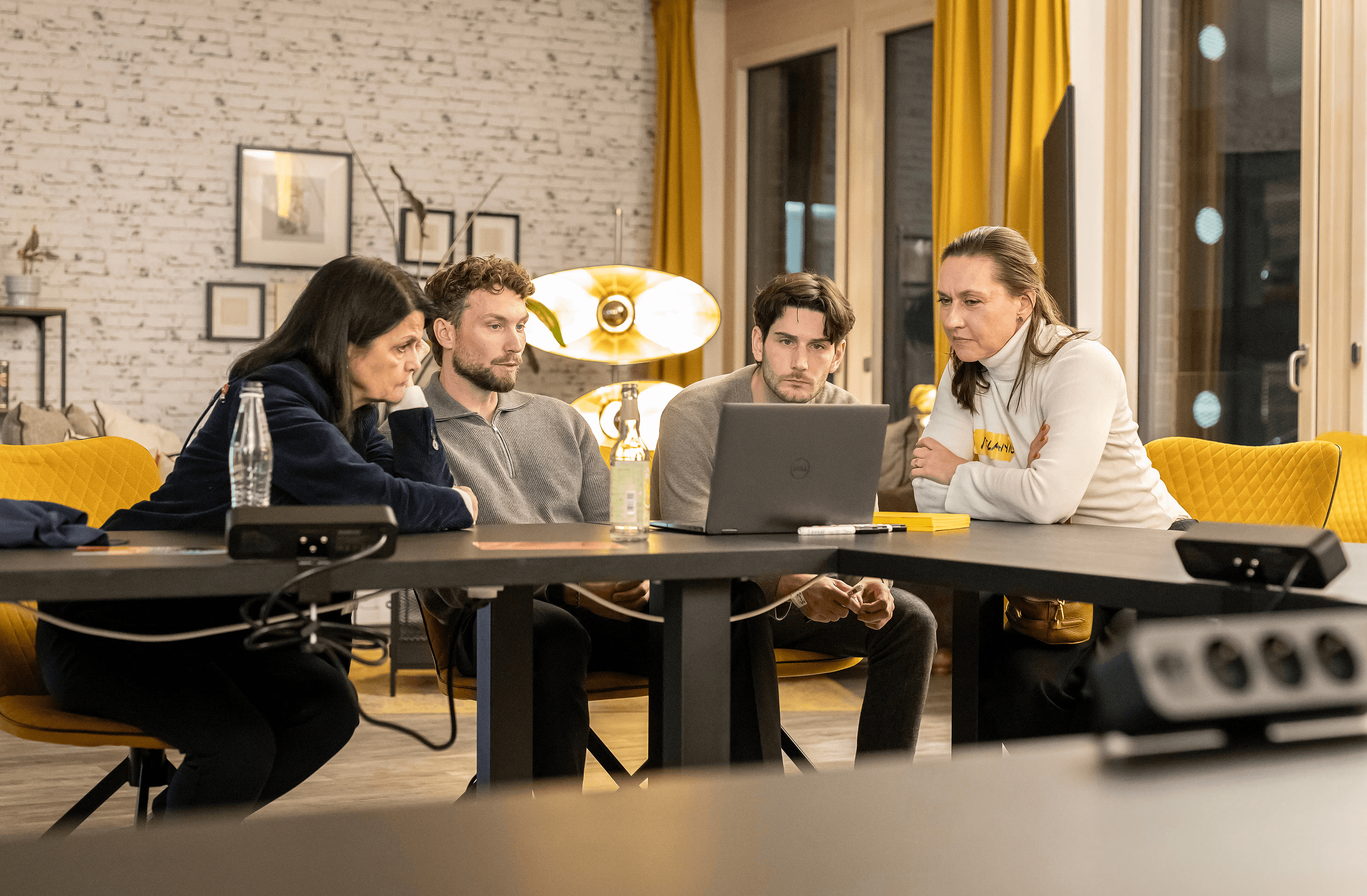 People crossing a busy street with cars and buildings.