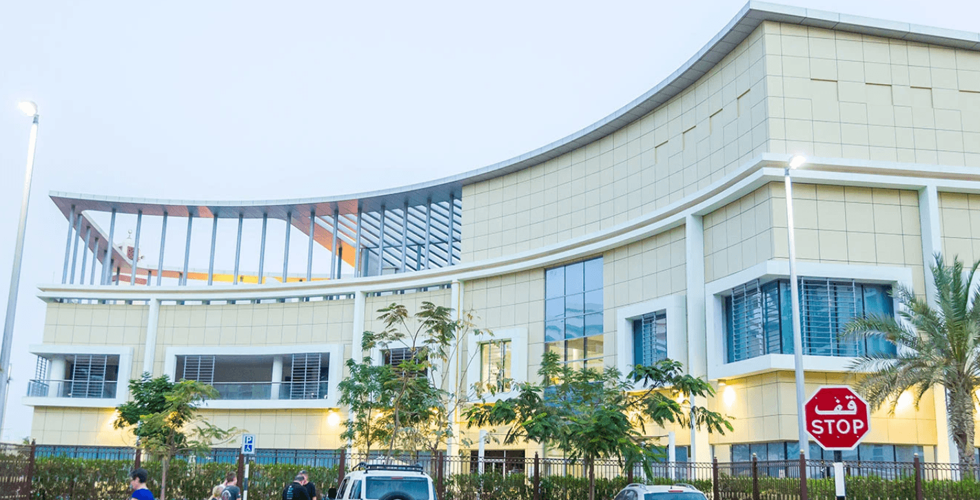 A scenic street in Khalifa City with lush trees and bushes in front of a home.