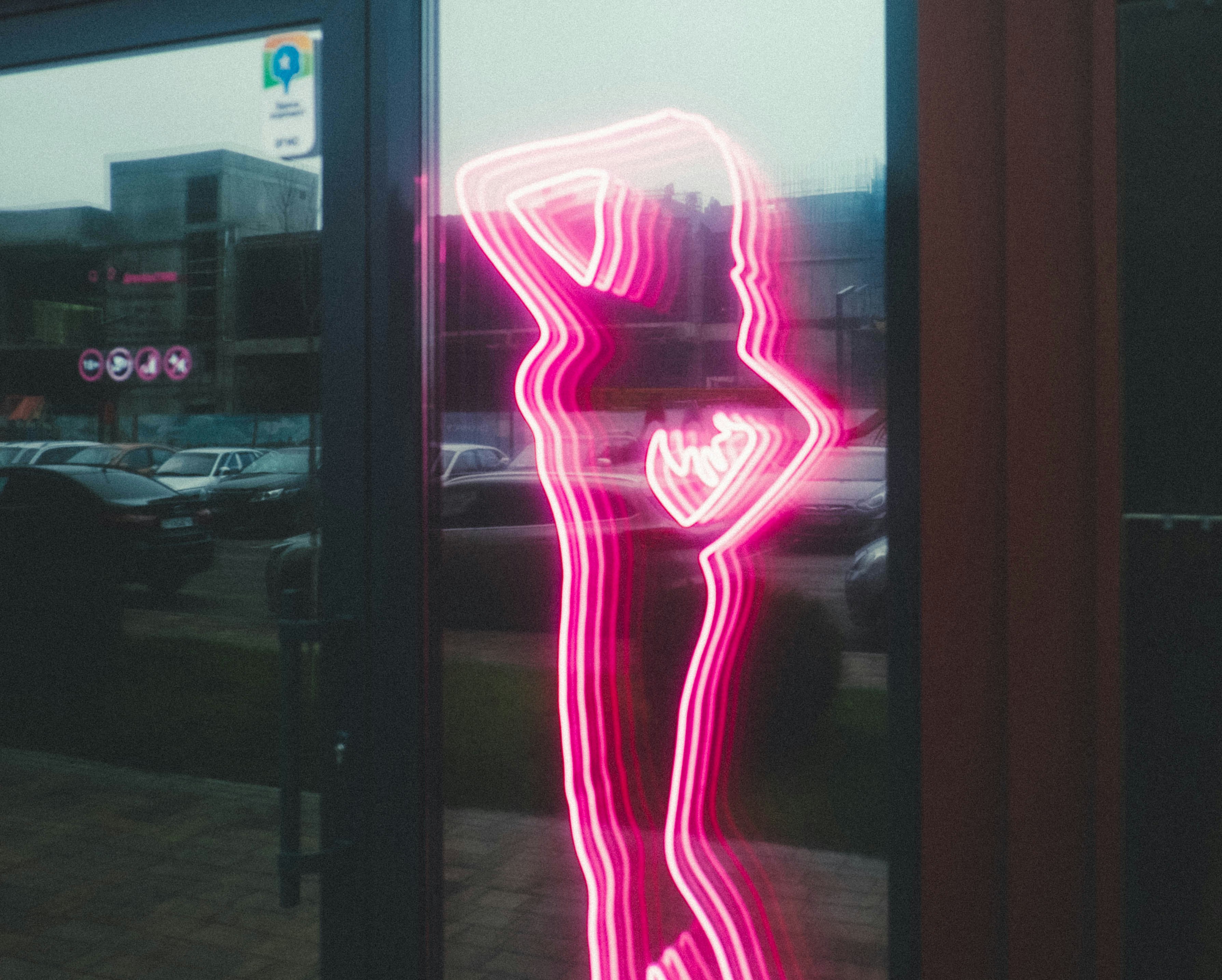 Neon silhouette of a woman on a glass surface.