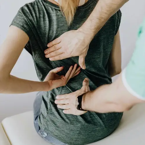 Provider performing a manual assessment of lower back pain in a clinical setting