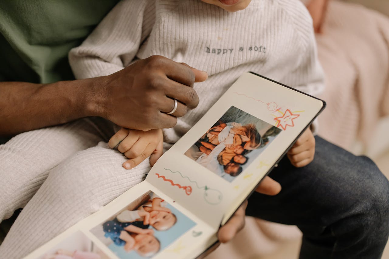Father showing son a baby photobook album of his first adventures with family.