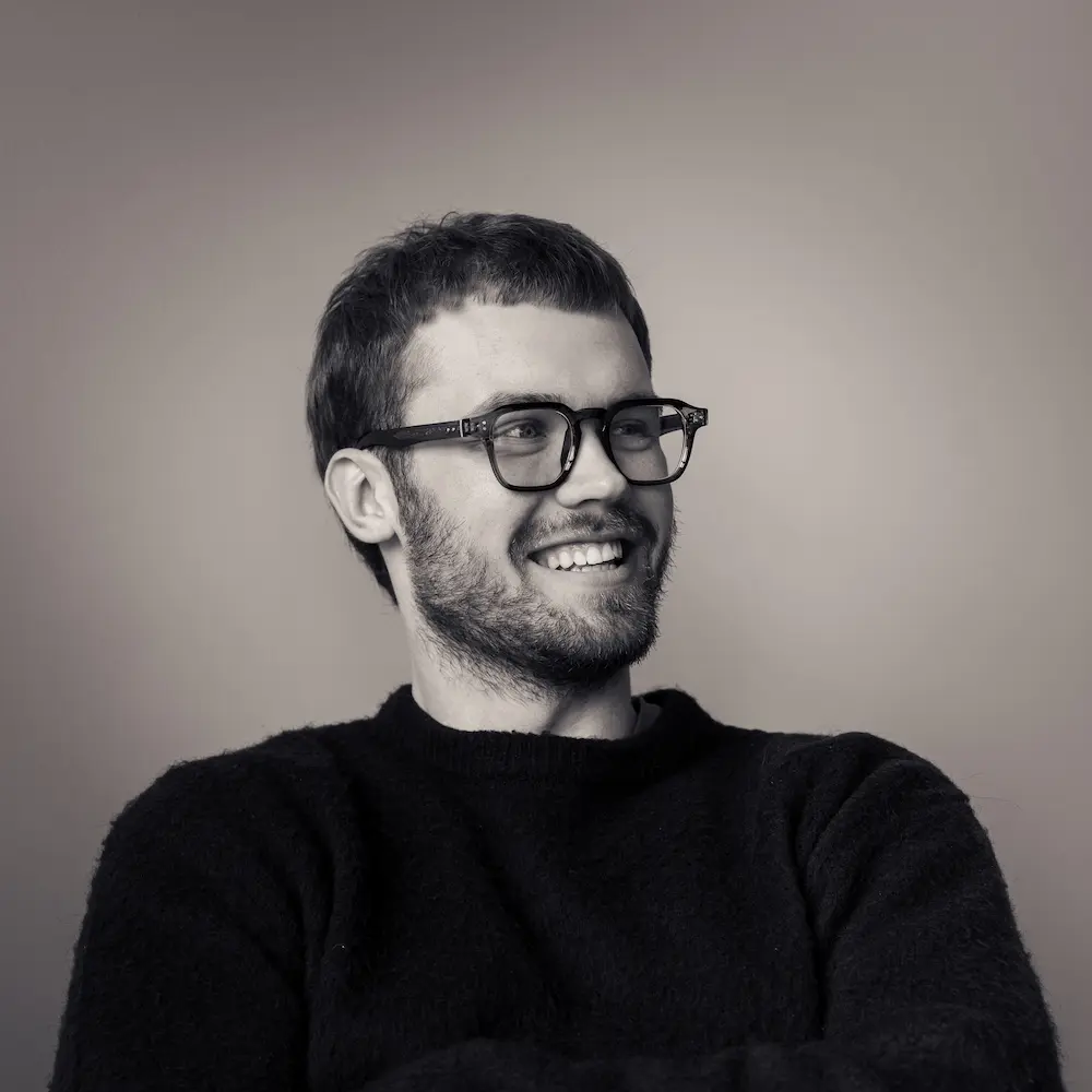 Portrait of a laughing person with curly hair wearing a white shirt