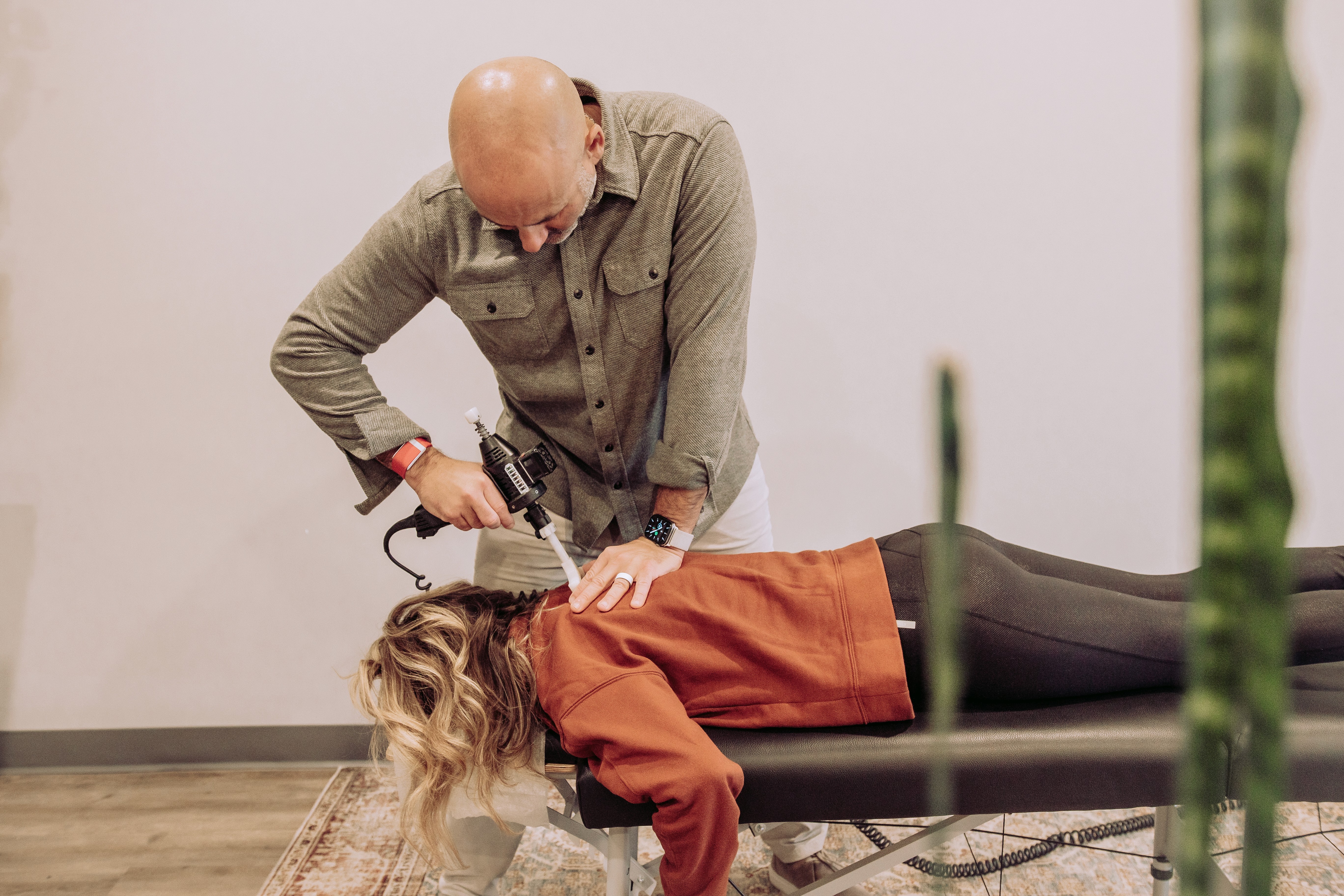 A man lying on a chiropractic table receiving lower spinal adjustments from a doctor.