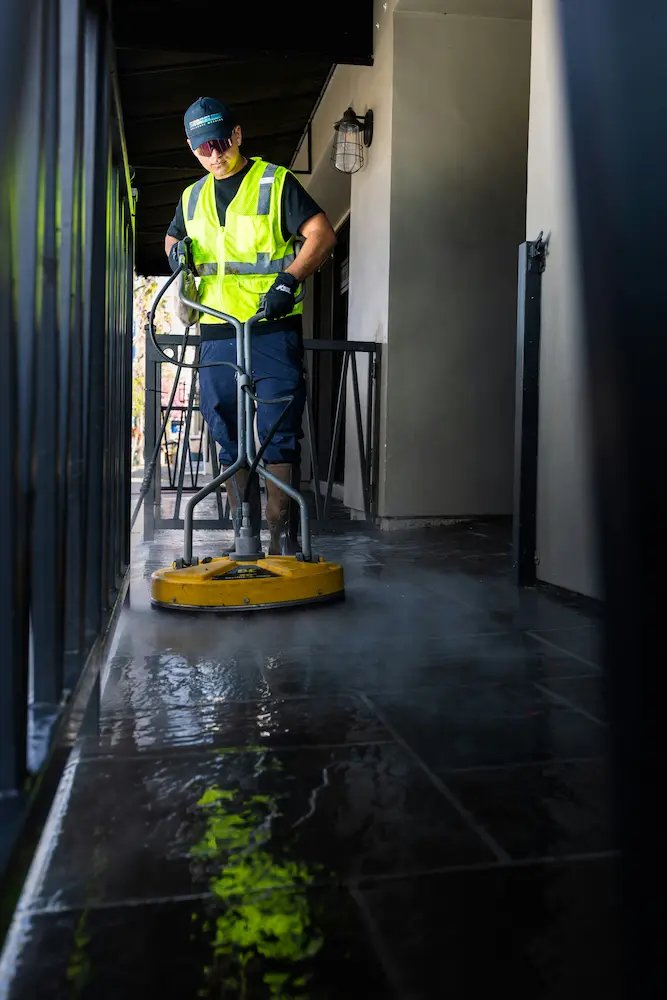 Professional using yellow floor polisher to clean and restore hard floor surface