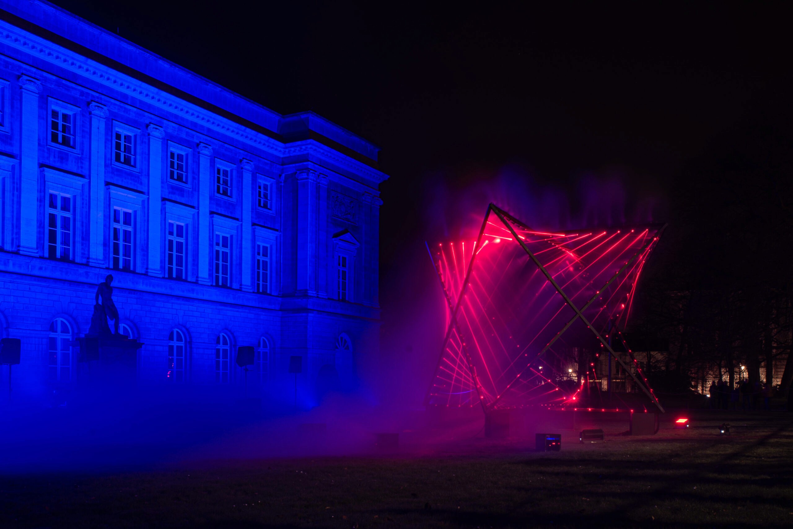 Building illuminated blue, abstract light sculpture glows red.