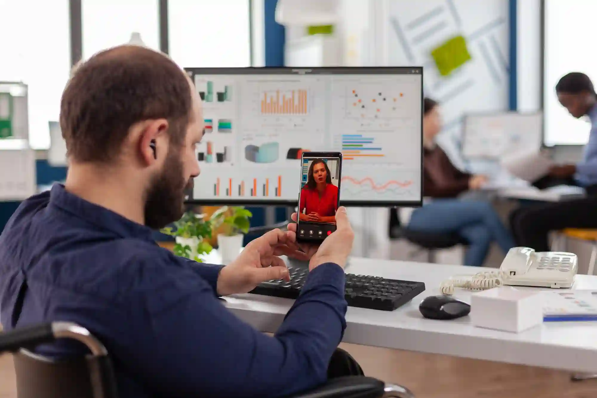 A man in a wheelchair on a video call at his desk.