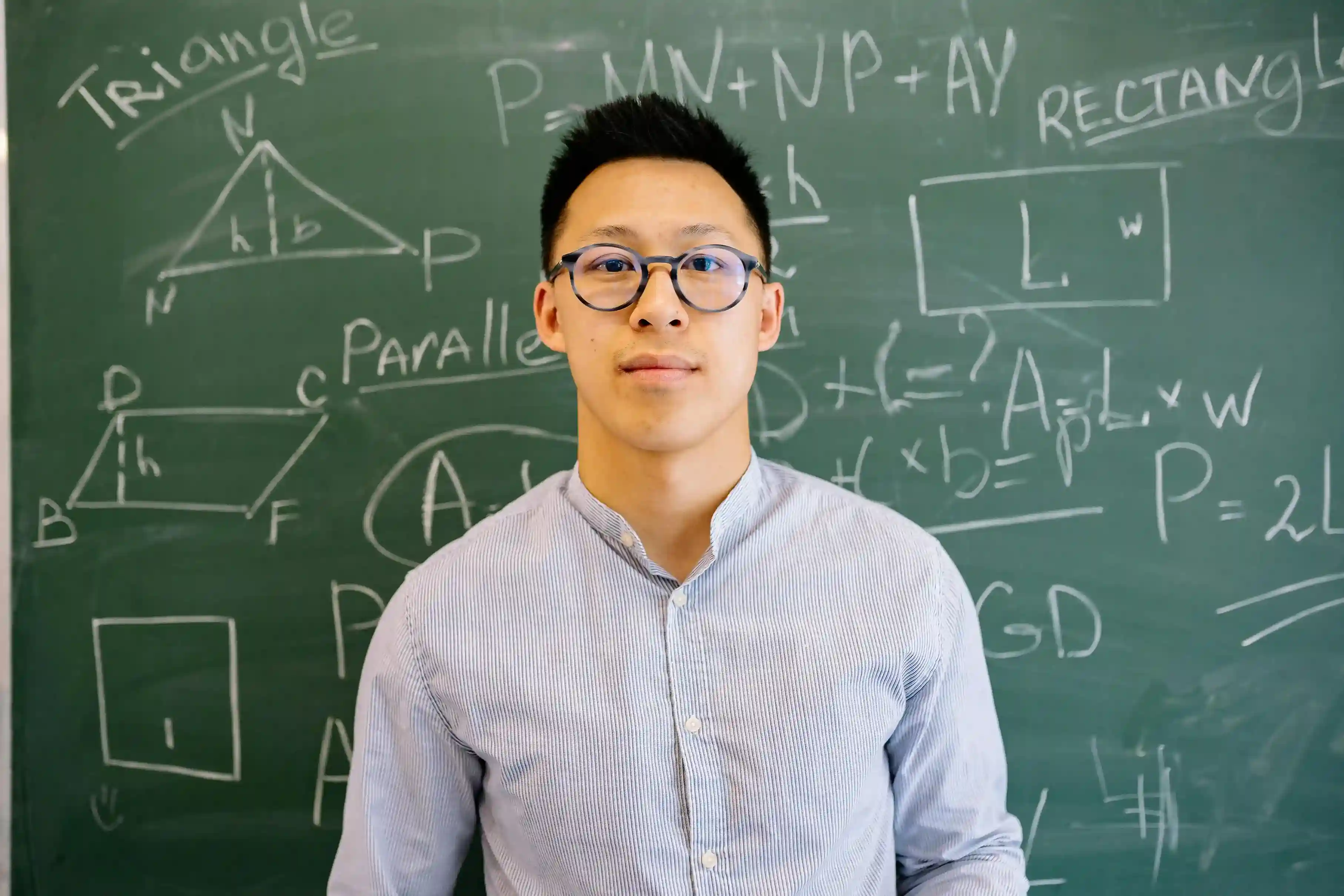 Secondary math tuition teacher explaining geometry and formulas on a classroom chalkboard for secondary students