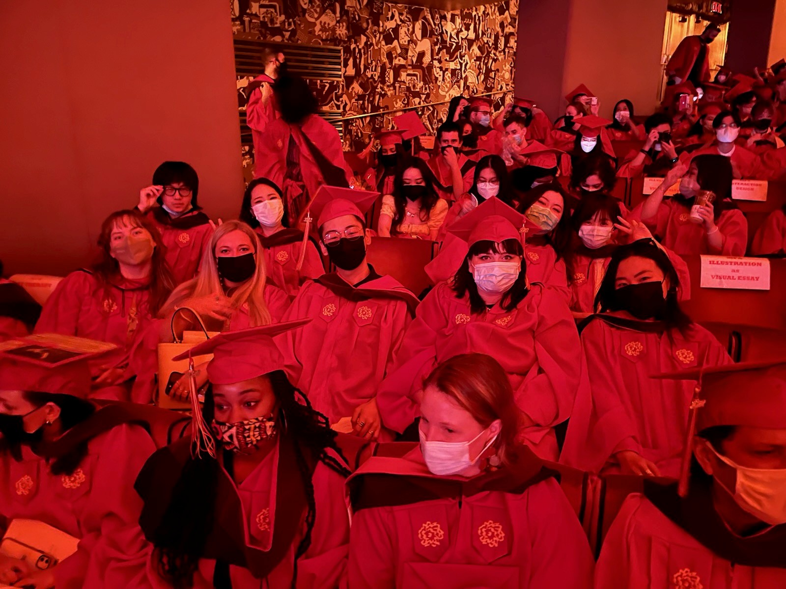 A red filtered photo of a group of grad students sitting in a festive hall.