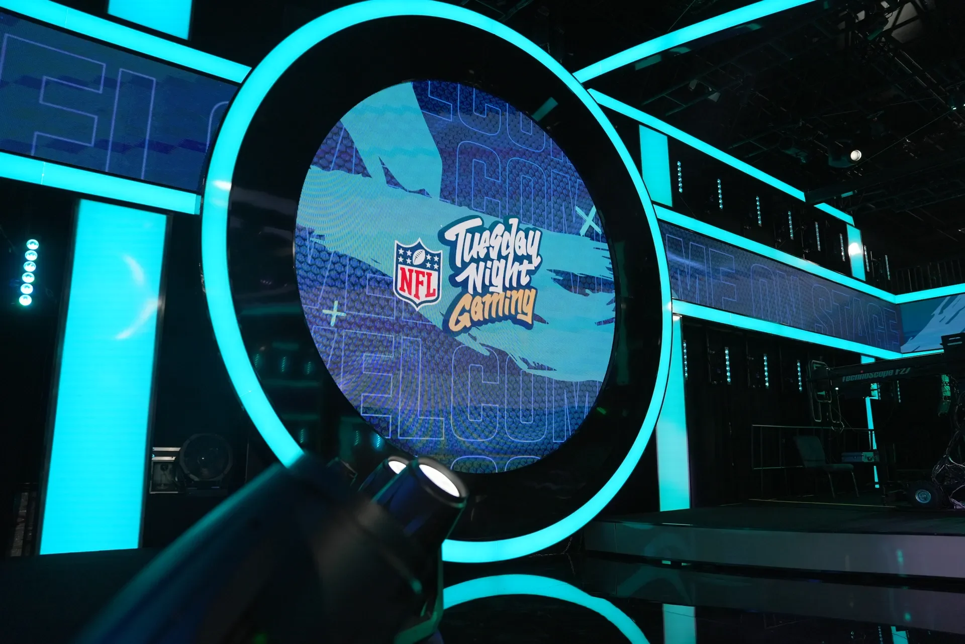 The Tuesday Night Gaming logo on a circular screen framed by teal studio lights
