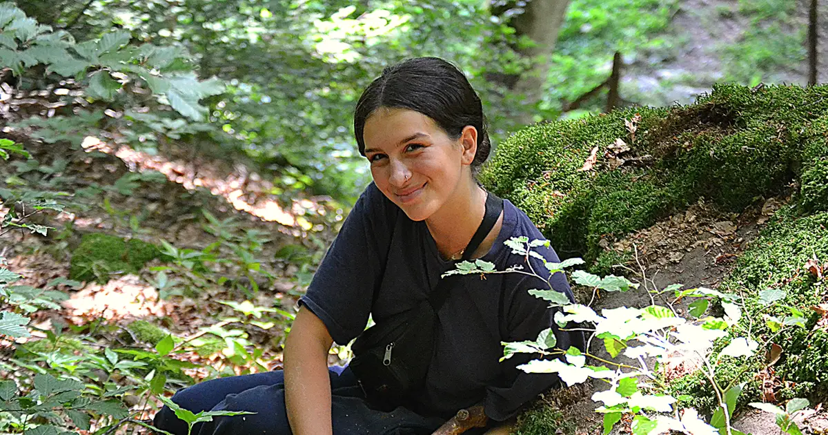 ragazza felice mentre intaglia il legno con tecniche di sopravvivenza bushcraft e indigeno primitive