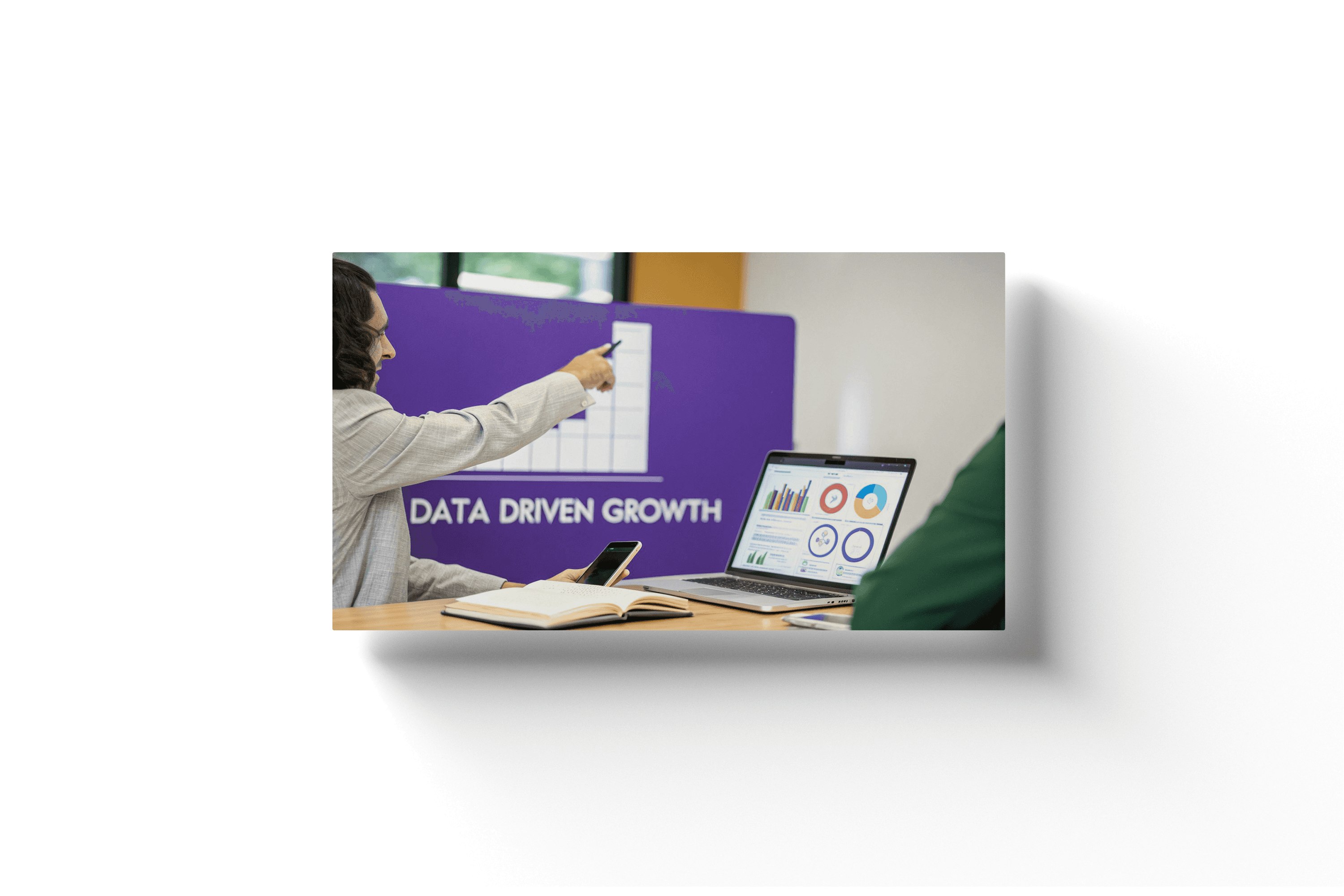 a laptop on a wooden desk with a woman pointing to a purple chart labeled 'data driven growth' in the background