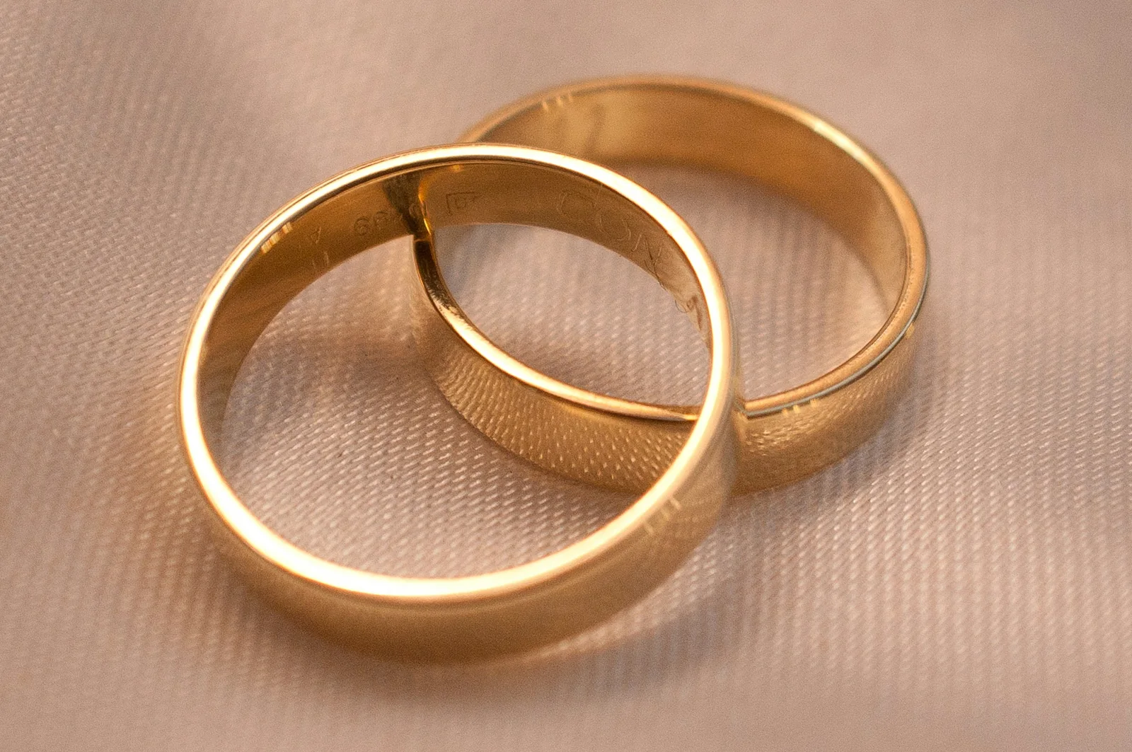 Two gold wedding rings on cream fabric