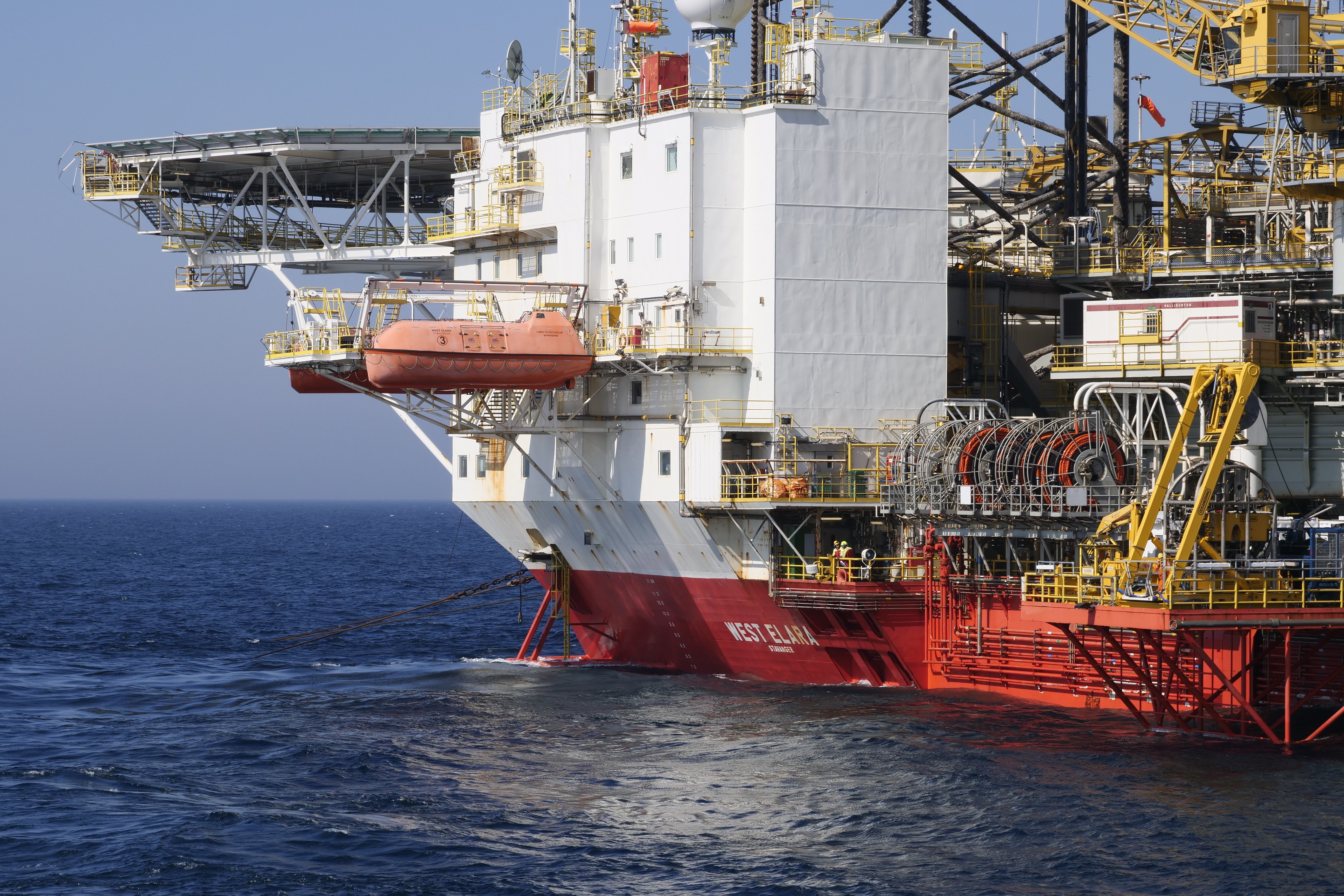 An offshore oil rig in the ocean featuring a large crane against a clear blue sky, by Automech Group