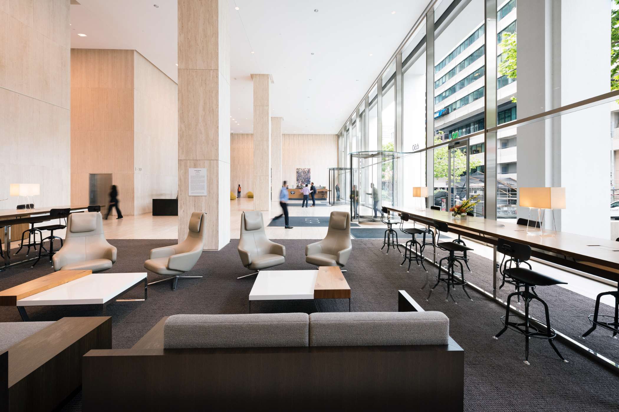 Modern office building with large windows reflecting a vivid orange sunset sky, silhouetted figure visible through the glass.