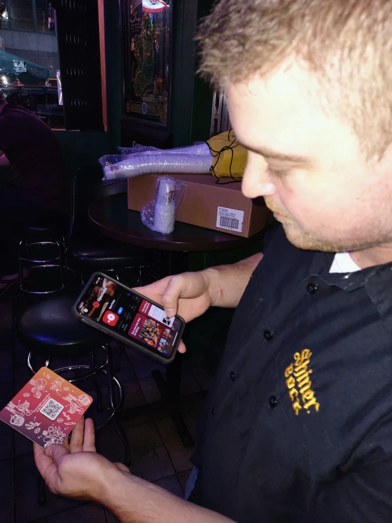 Customer holding an OpenTable coaster while looking at a phone