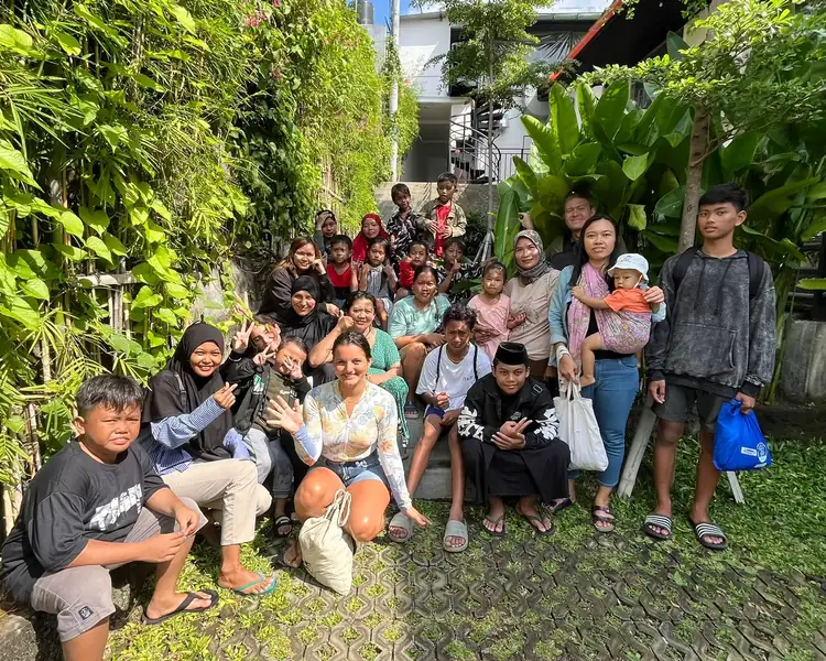 Smiling group of volunteers, parents, and children gathered together after a donation sorting and distribution day.