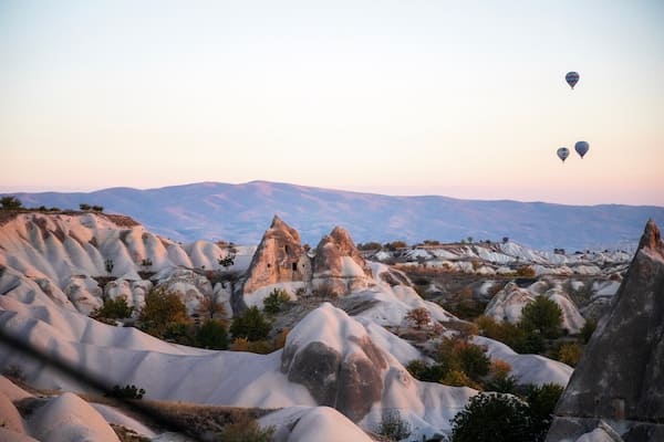 Cappadocia at sunrise with hot air balloons and unique rock formations.