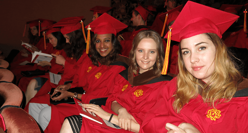 A group of grad students wearing red SVA robes and hats with gold yellow logos of the school.