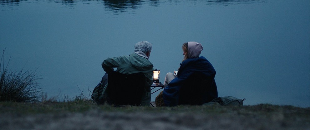 Woman and men sitting cozy at a lake