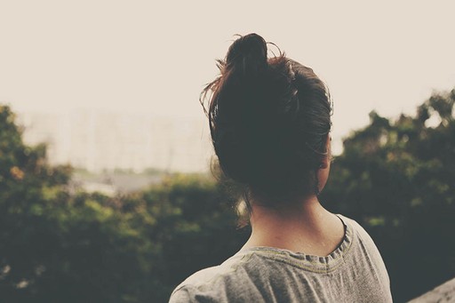 Ambigous photo of a woman with dark hair looking out over a park
