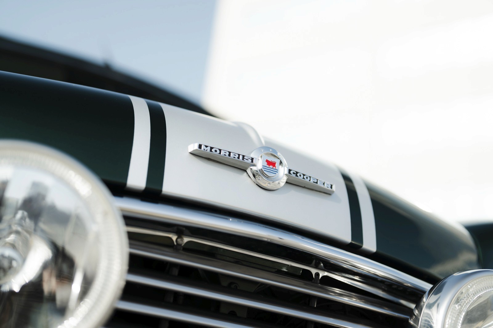 Close-up of a car's front grille and logo, showcasing sleek design and chrome details against a clear sky.