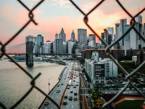 photo taken through broken chain link fence overlooking a city skyline
