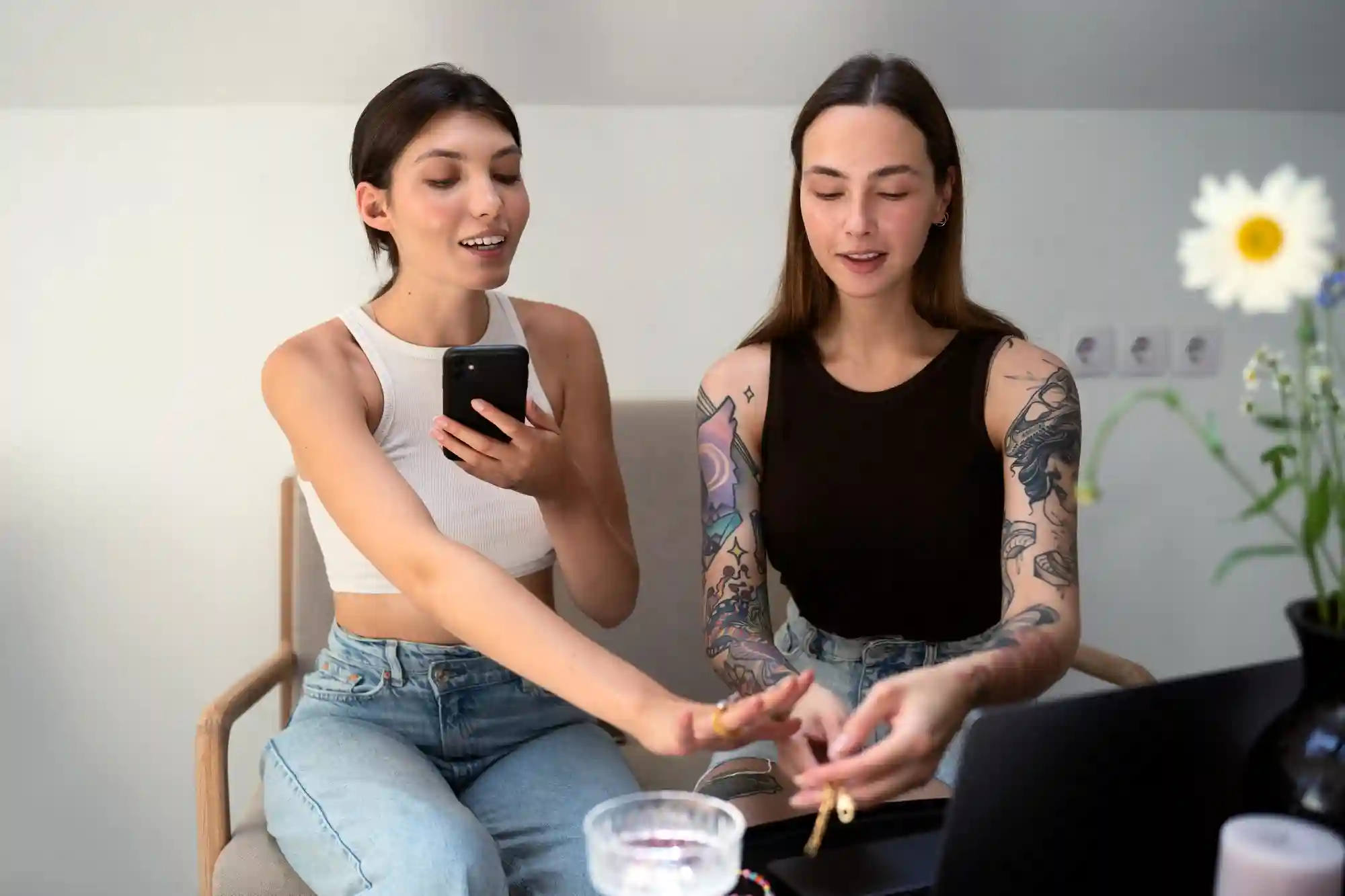 Two women discussing jewelry, one is looking at a phone.