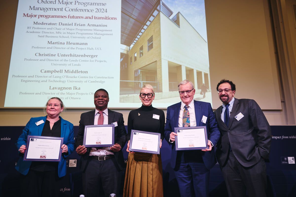 Four conference speakers holding certificates together outside the Saïd Business School venue at the Oxford Major Programme Alliance conference
