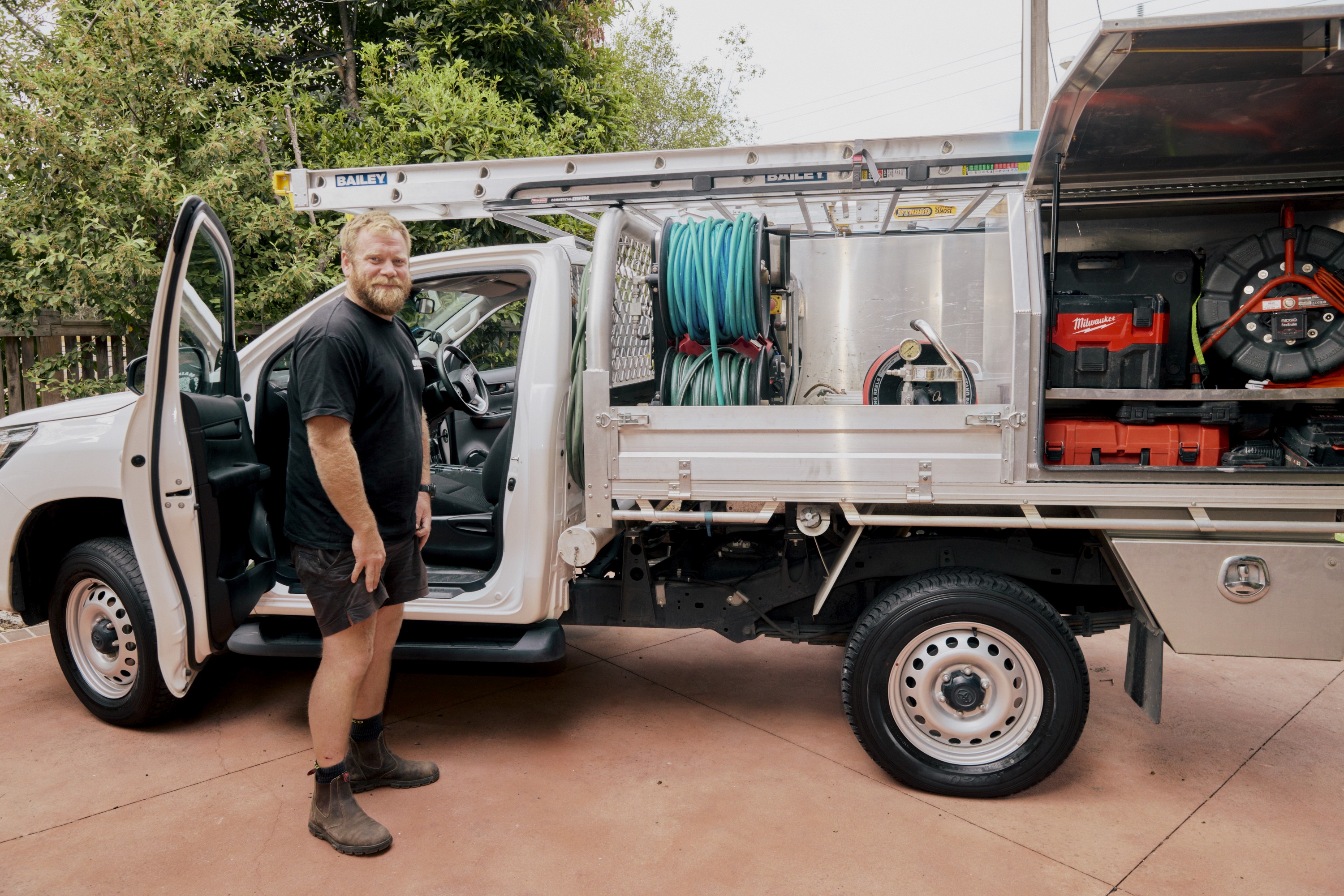 Good Maintenance Plumber uncoiling a hose from the back of a company ute.
