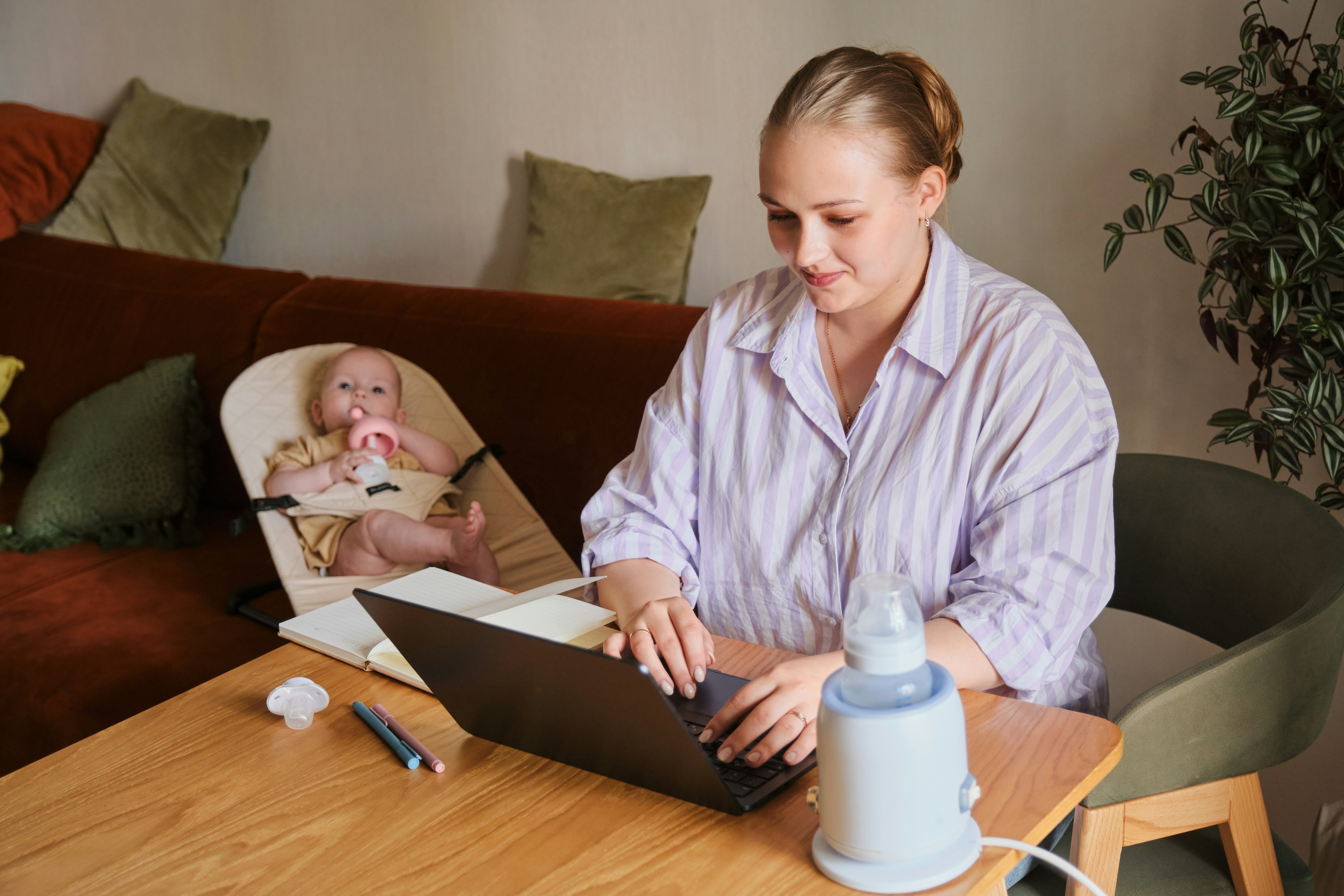mother works on computer with baby in background