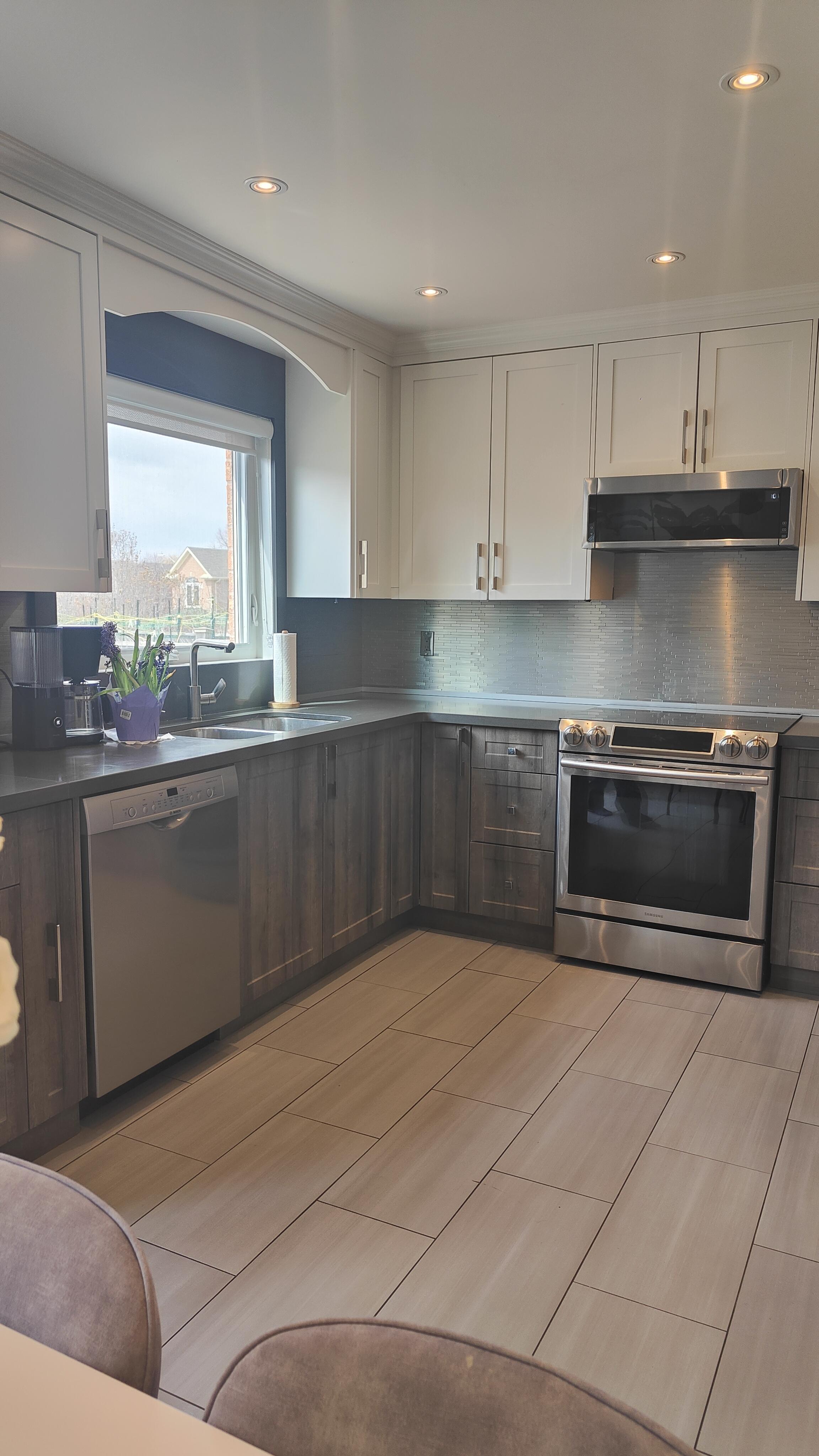 The inherited kitchen: white uppers, dark wood lowers, gray counters and backsplash