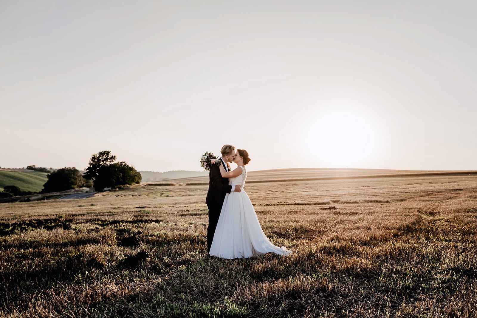 A couple in formal wedding attire embraces intimately in a vast.