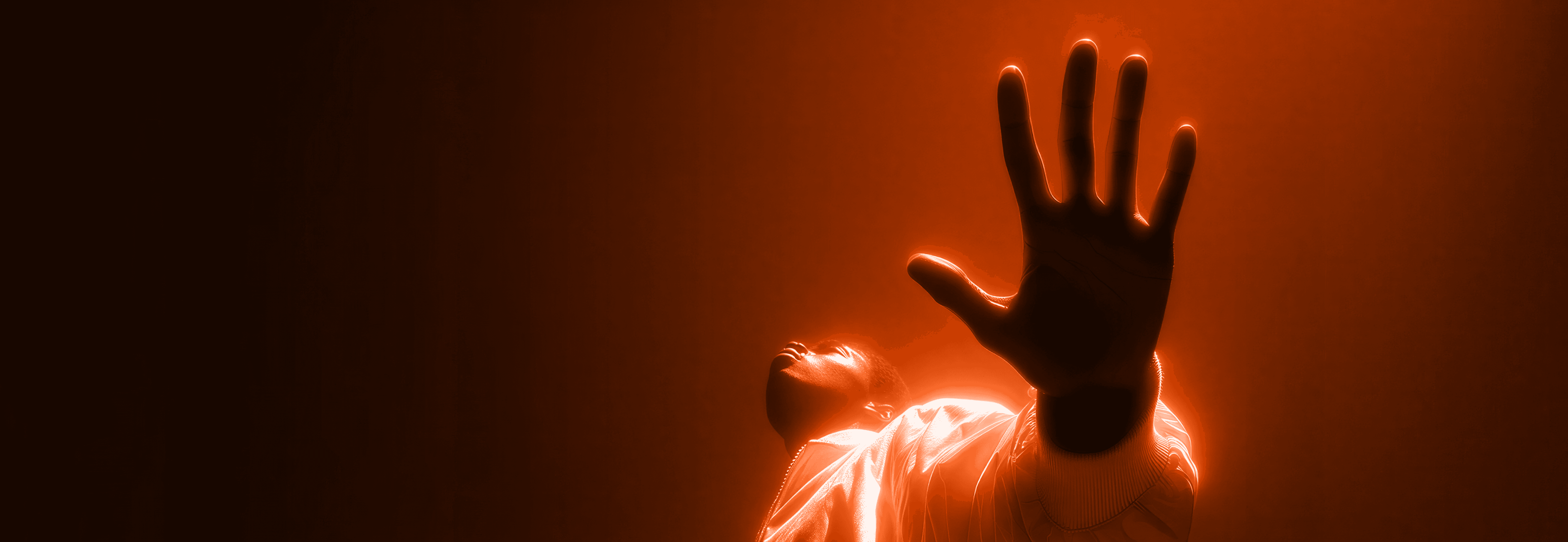 Person reaching upward with glowing orange light