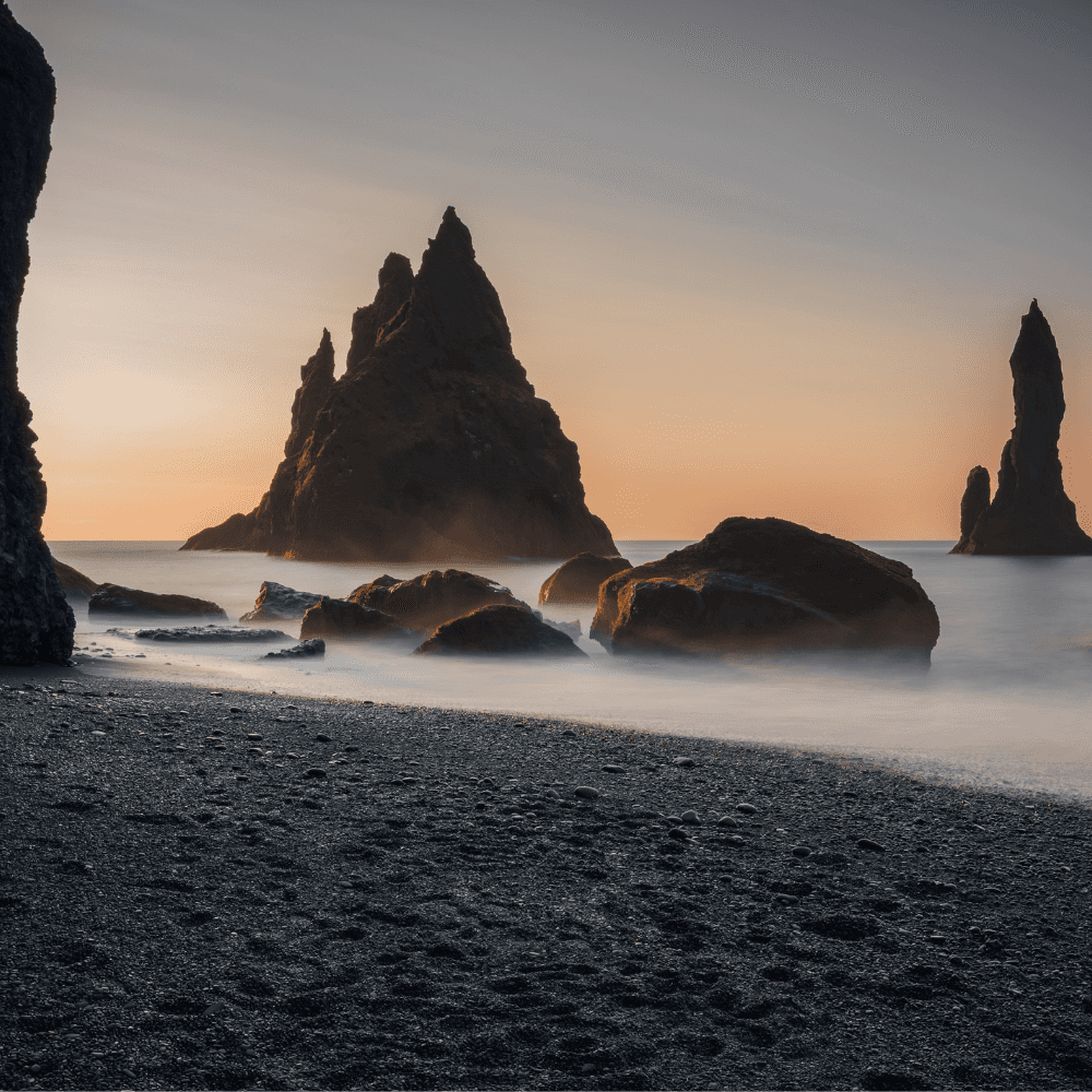 The sea stacks at Reynisfjara shown in the golden hour. In the forefront is Reynisfjara beach near the village of Vík in Iceland.