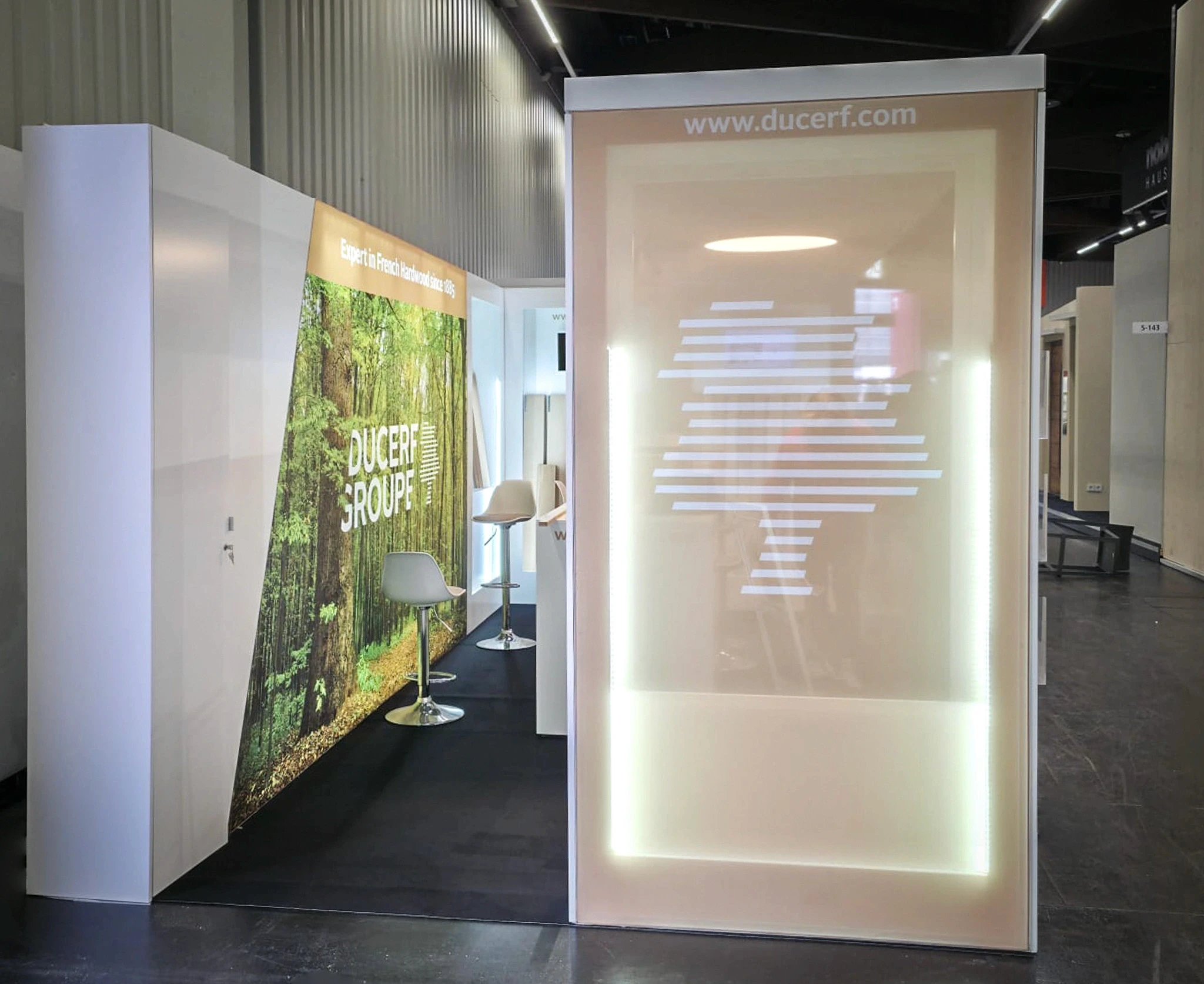 Stand Ducerf Groupe bois feuillus français conçu par EXPACE au Carrefour International du Bois (CIB) 2026 — visuel forestier, comptoir en bois massif et échantillons d'essences rétroéclairés