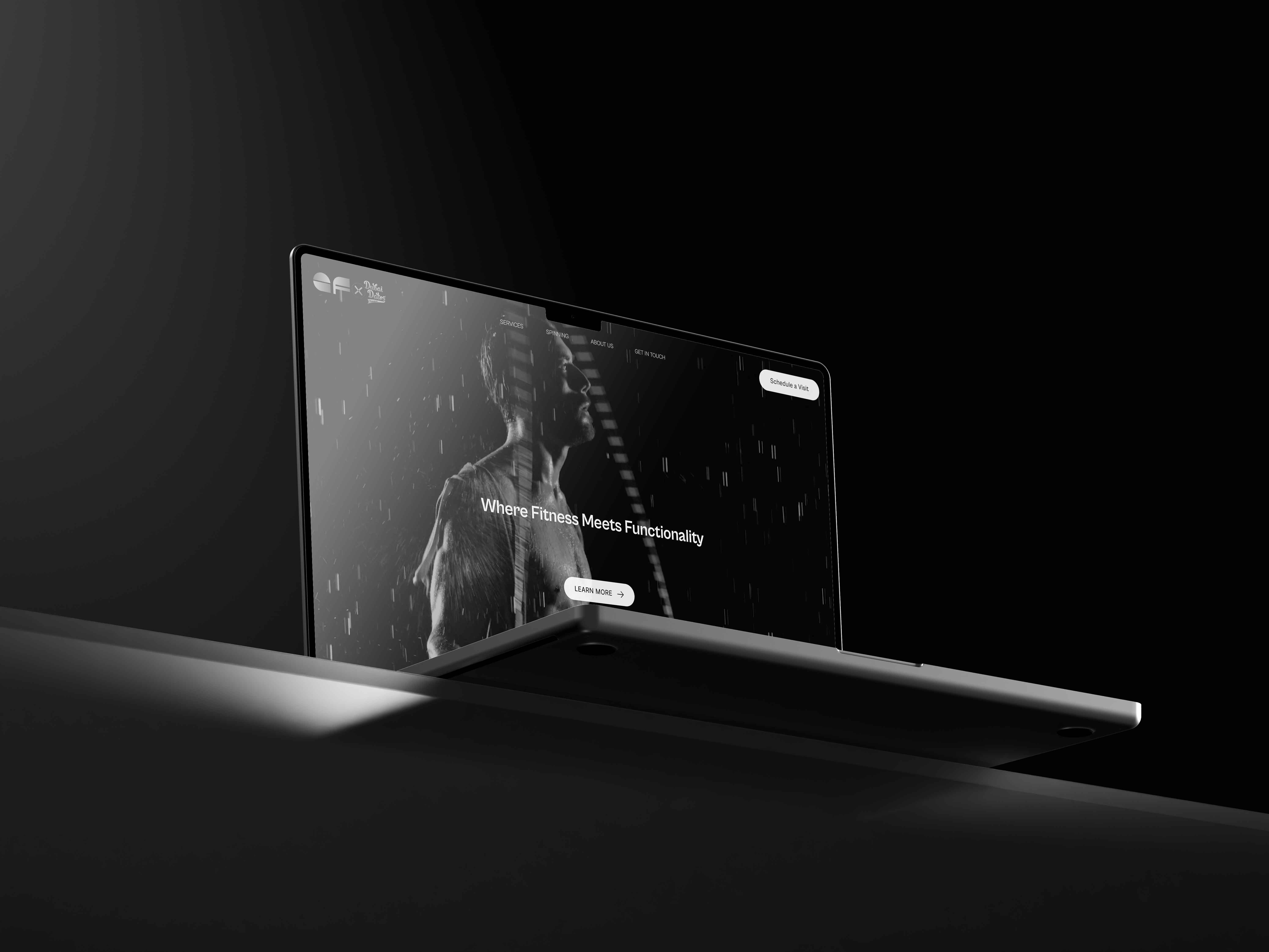 Laptop computer on a desk in a black background. In the screen the Elite Fit website homepage with a man doing gymnastics.